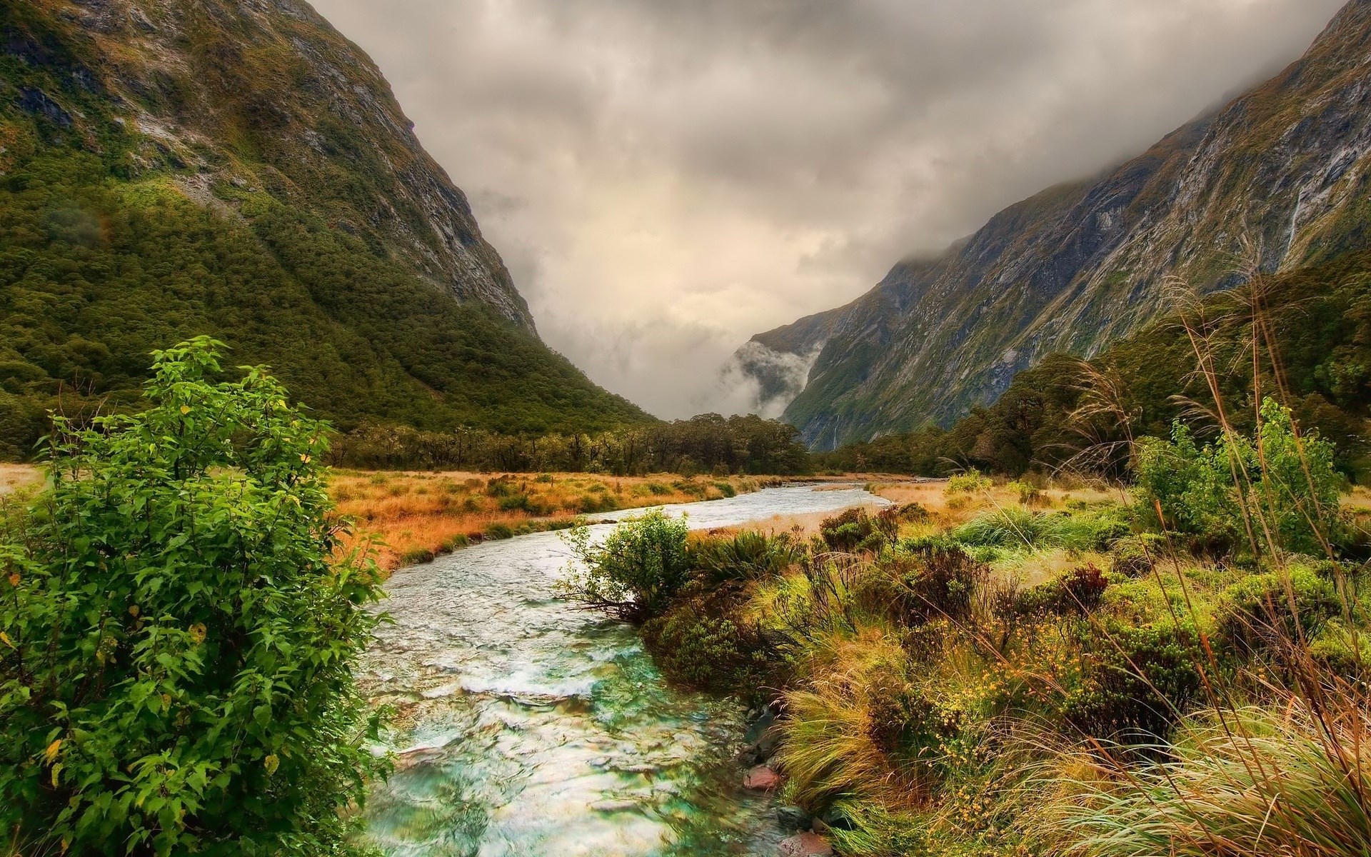 River flowing through a valley with mountains and clouds HD Wallpaper
