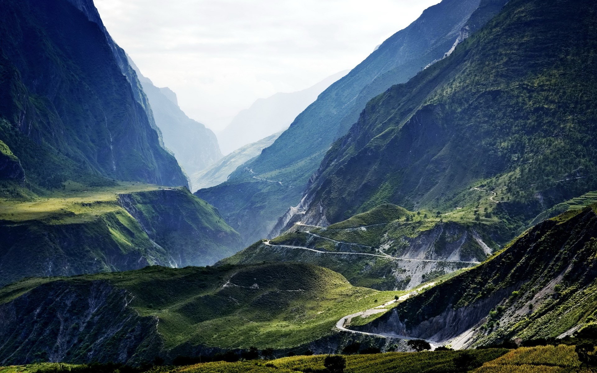 Winding road through a deep mountain valley HD Wallpaper