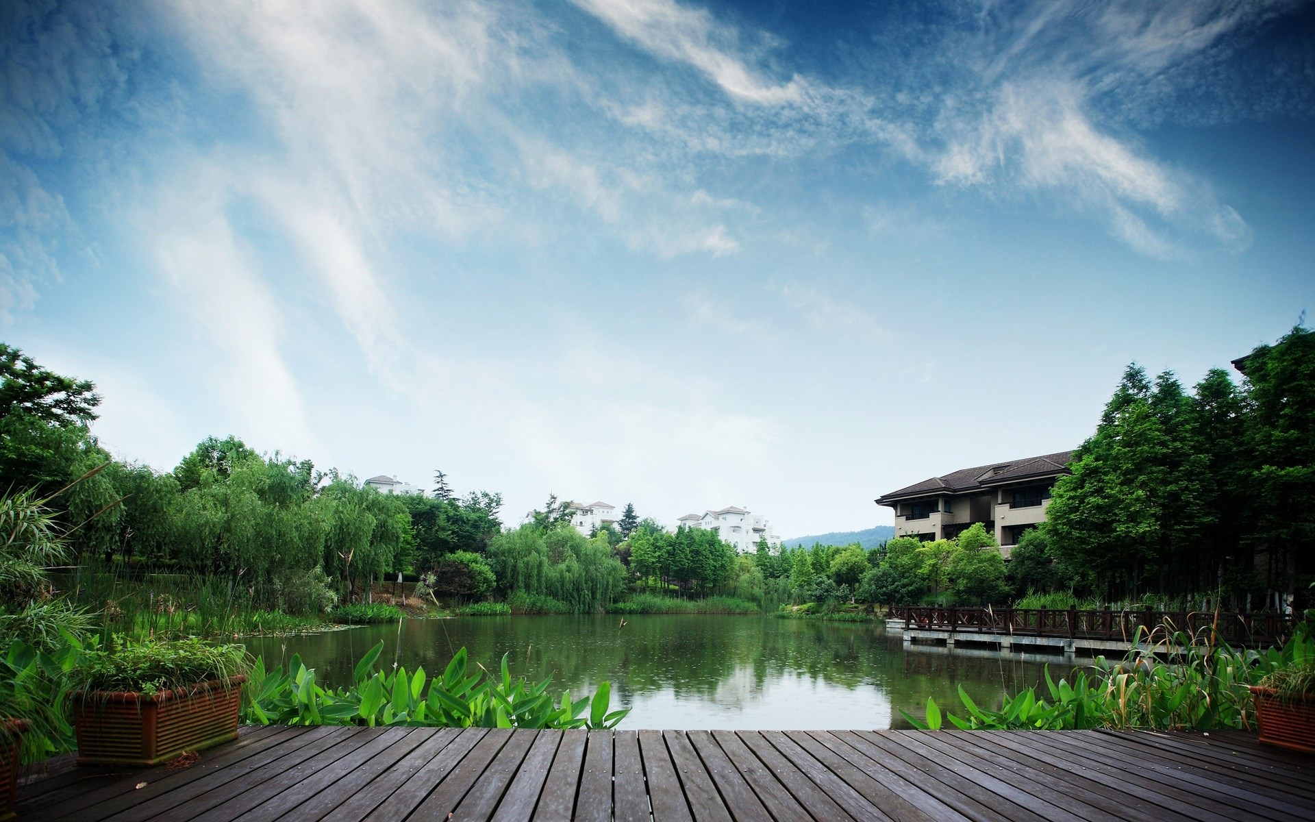 Wooden deck overlooking a tranquil lake and greenery HD Wallpaper
