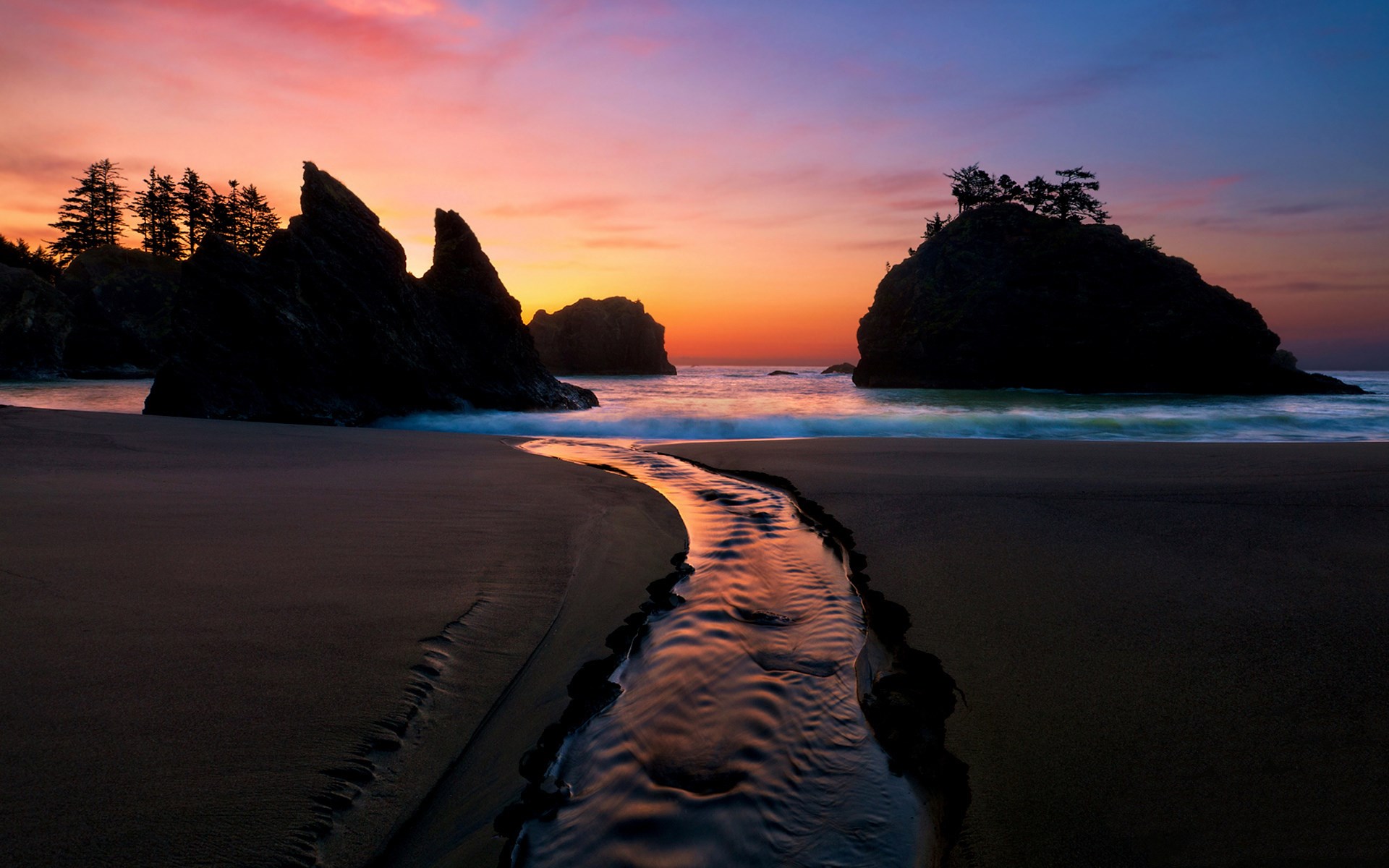 Sunset over a beach with a stream and rock formations HD Wallpaper
