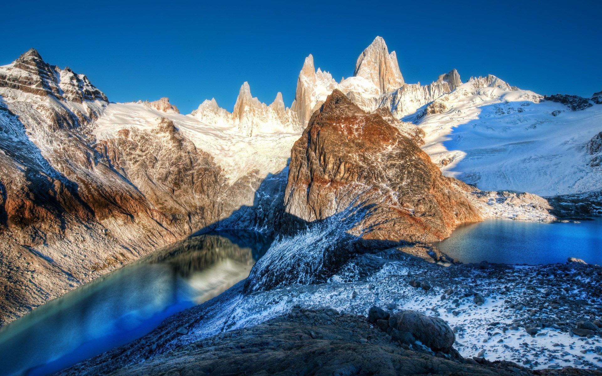 Snow-capped mountains and a blue lake under a clear sky HD Wallpaper