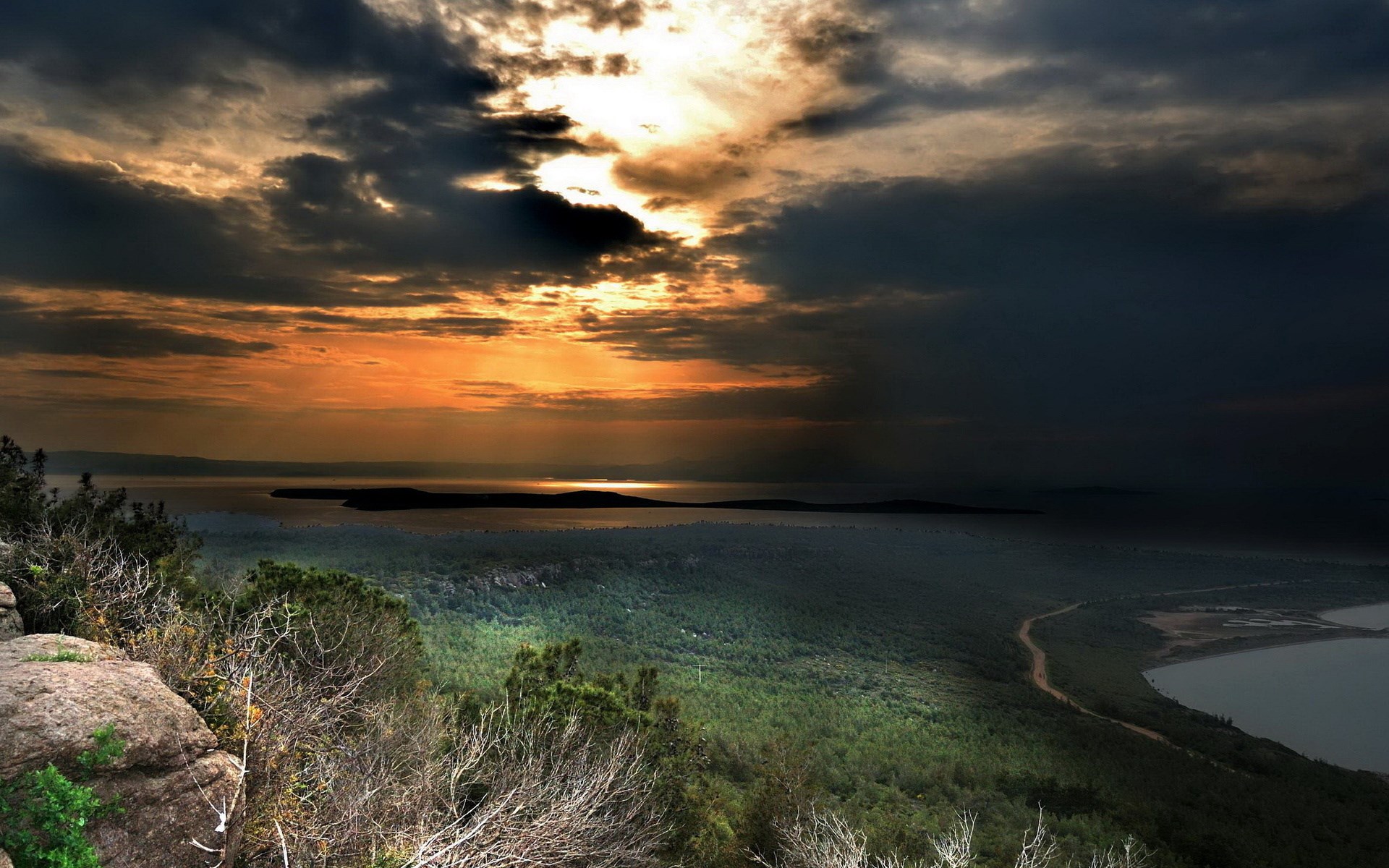 Dramatic sunset over a forested coastline and sea HD Wallpaper