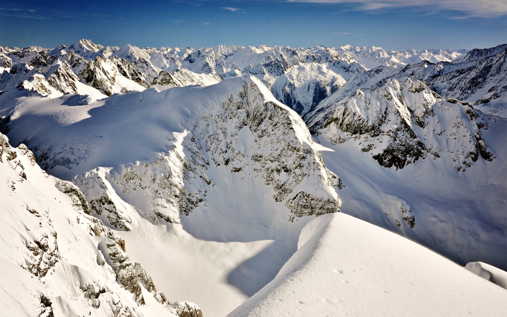 Snow-covered mountain range under a clear blue sky HD Wallpaper