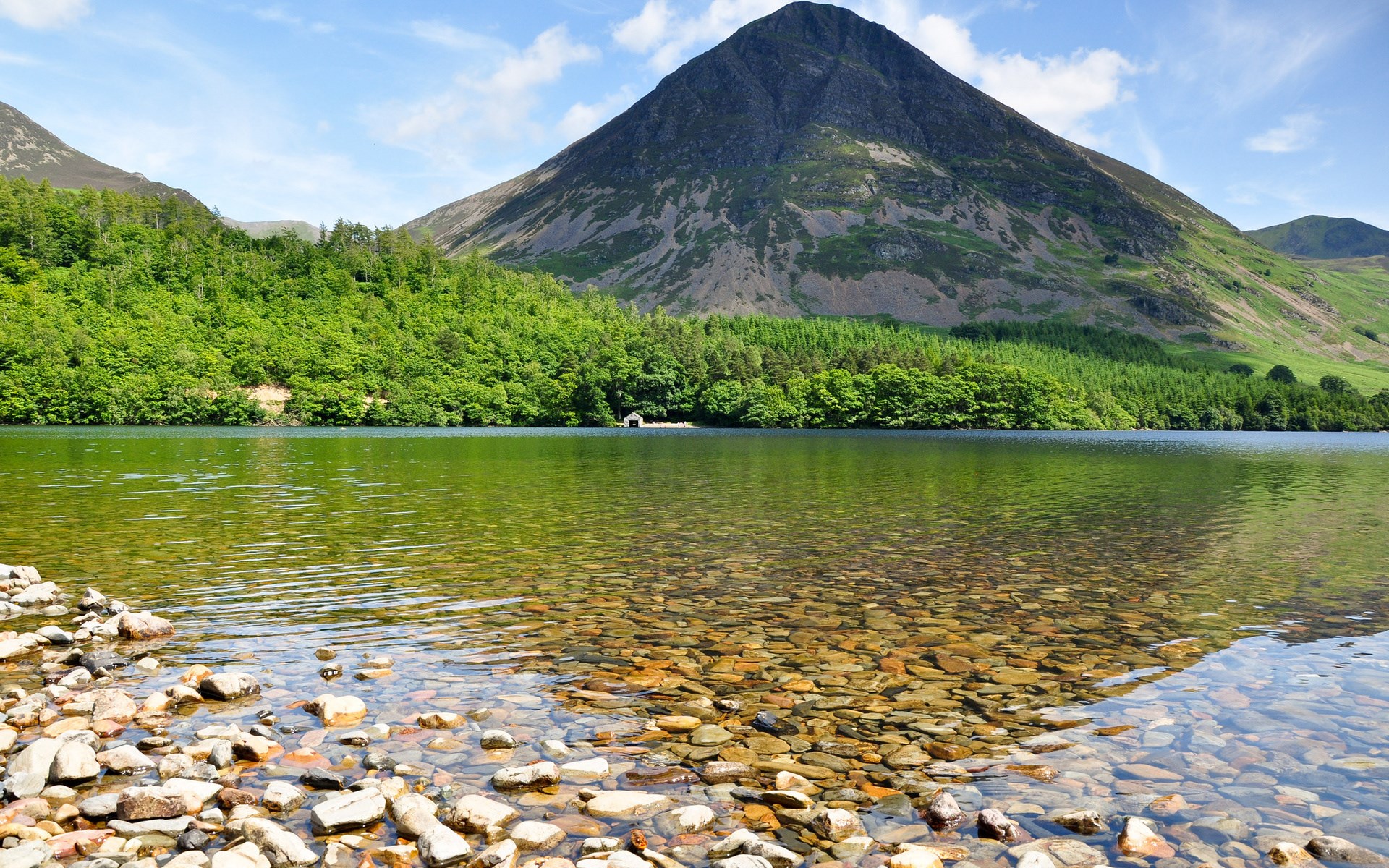 Mountain lake with rocky shore and green forest HD Wallpaper
