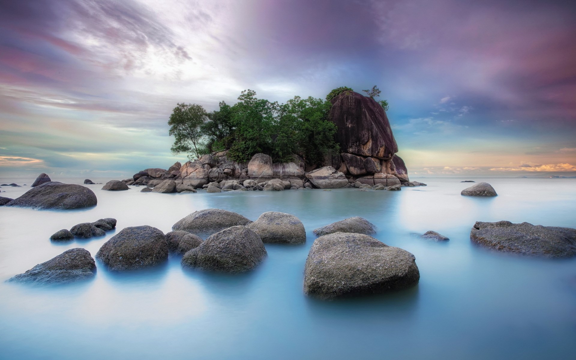 Rocky island with trees in calm ocean water at sunset HD Wallpaper