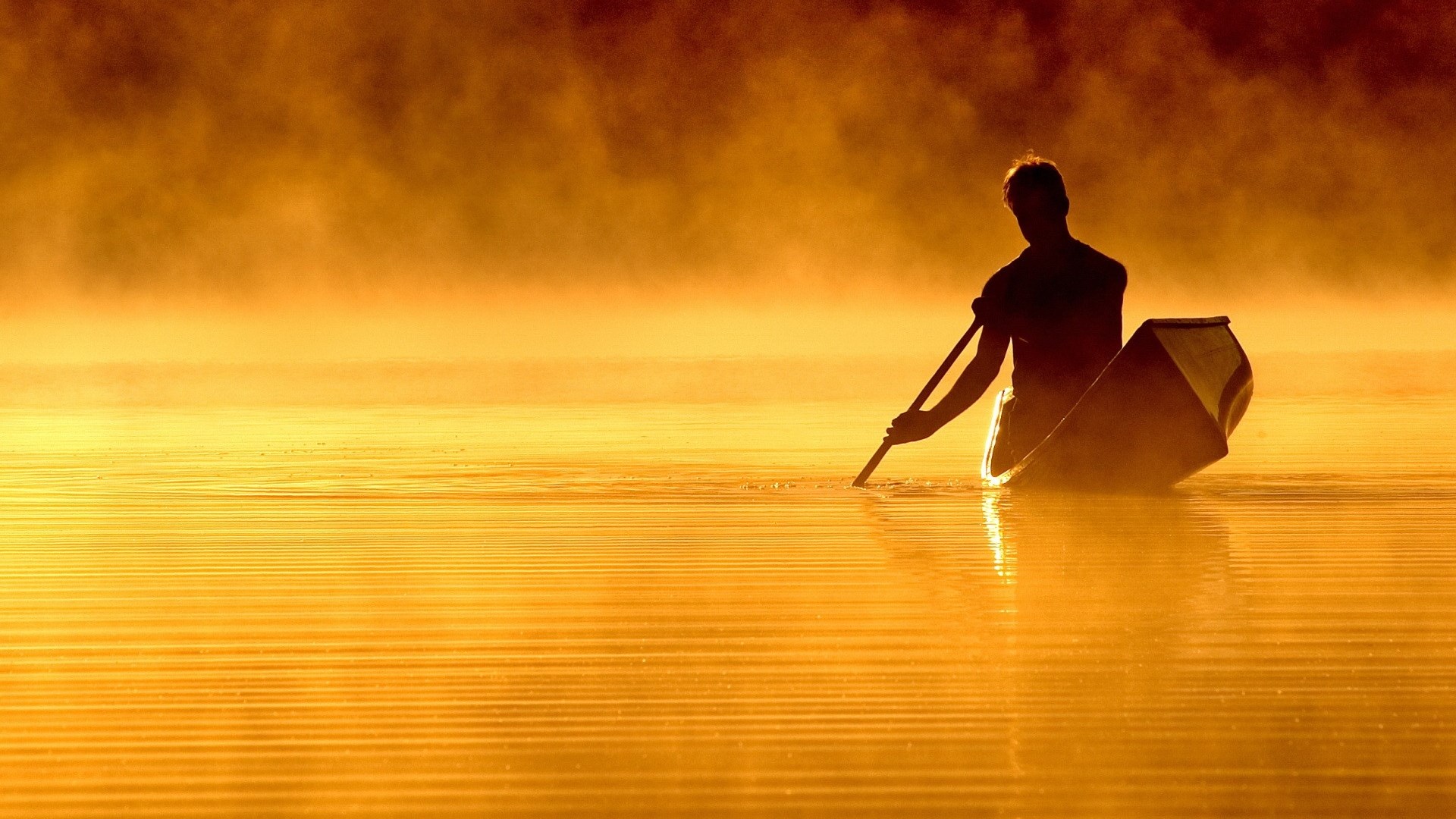Man in a canoe paddling through misty water at sunrise HD Wallpaper