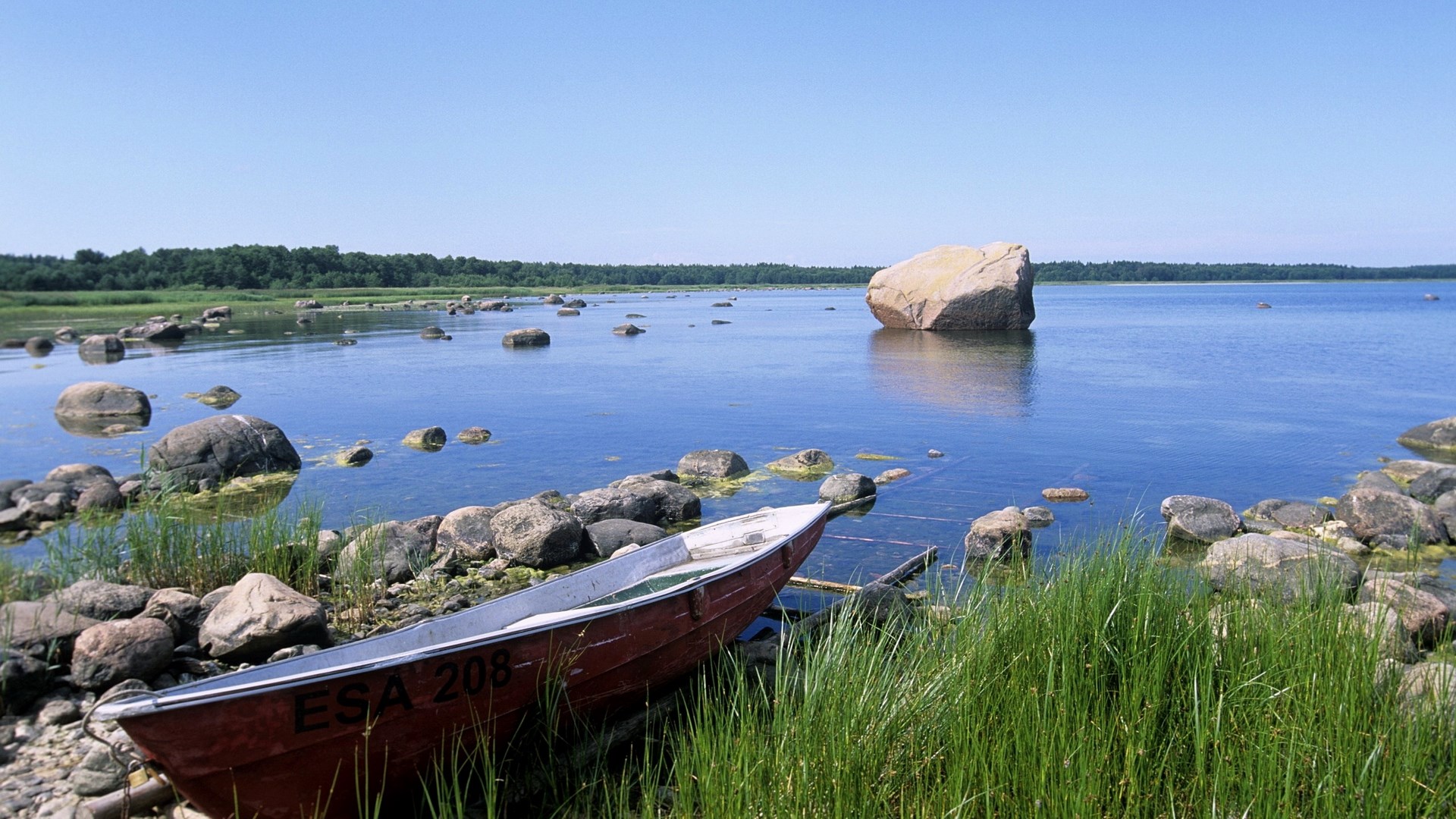 Boat on a rocky shore with a large boulder in the water HD Wallpaper