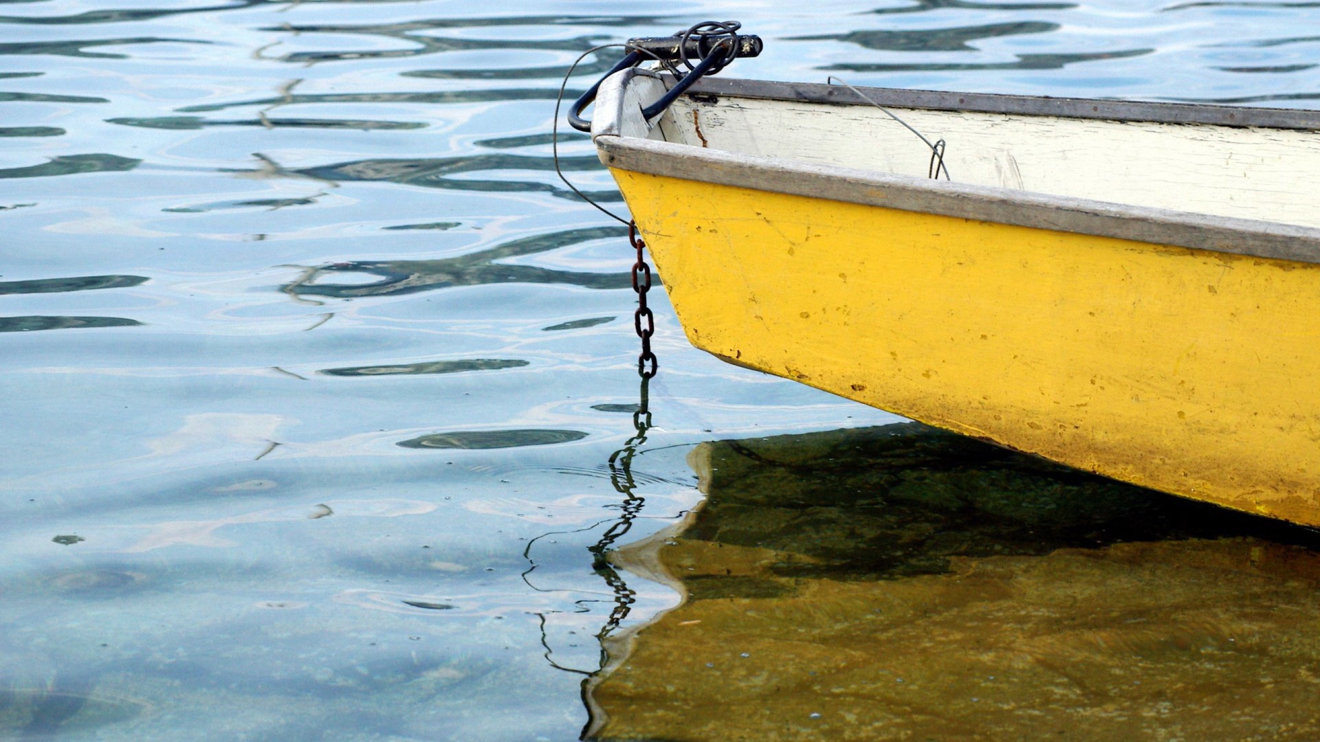 Yellow boat tied with a chain on rippling water HD Wallpaper