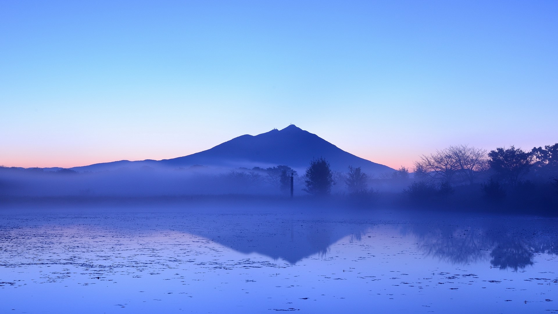 Misty mountain reflected in a calm lake at dawn HD Wallpaper