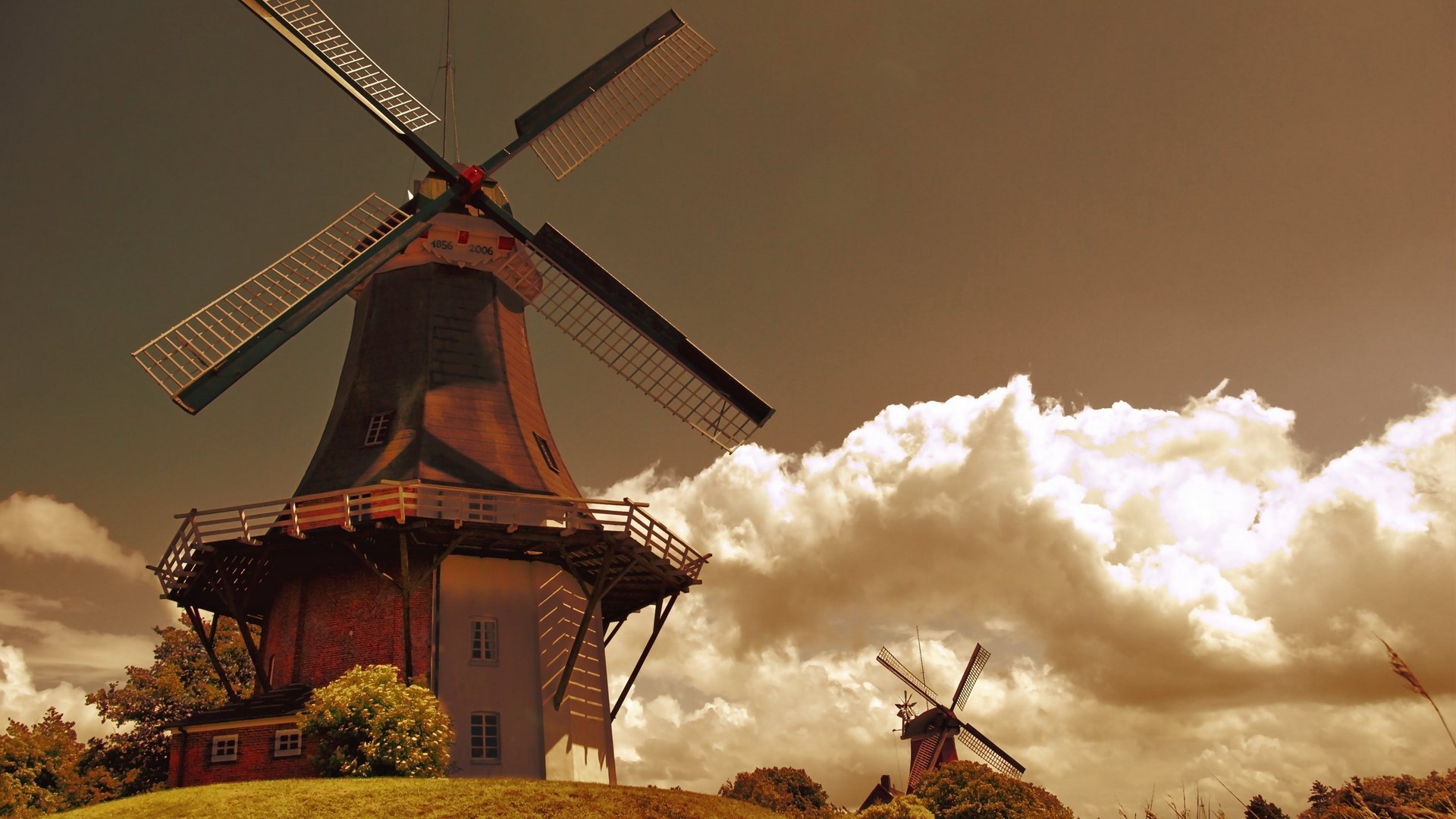 Two windmills on a grassy hill with clouds HD Wallpaper