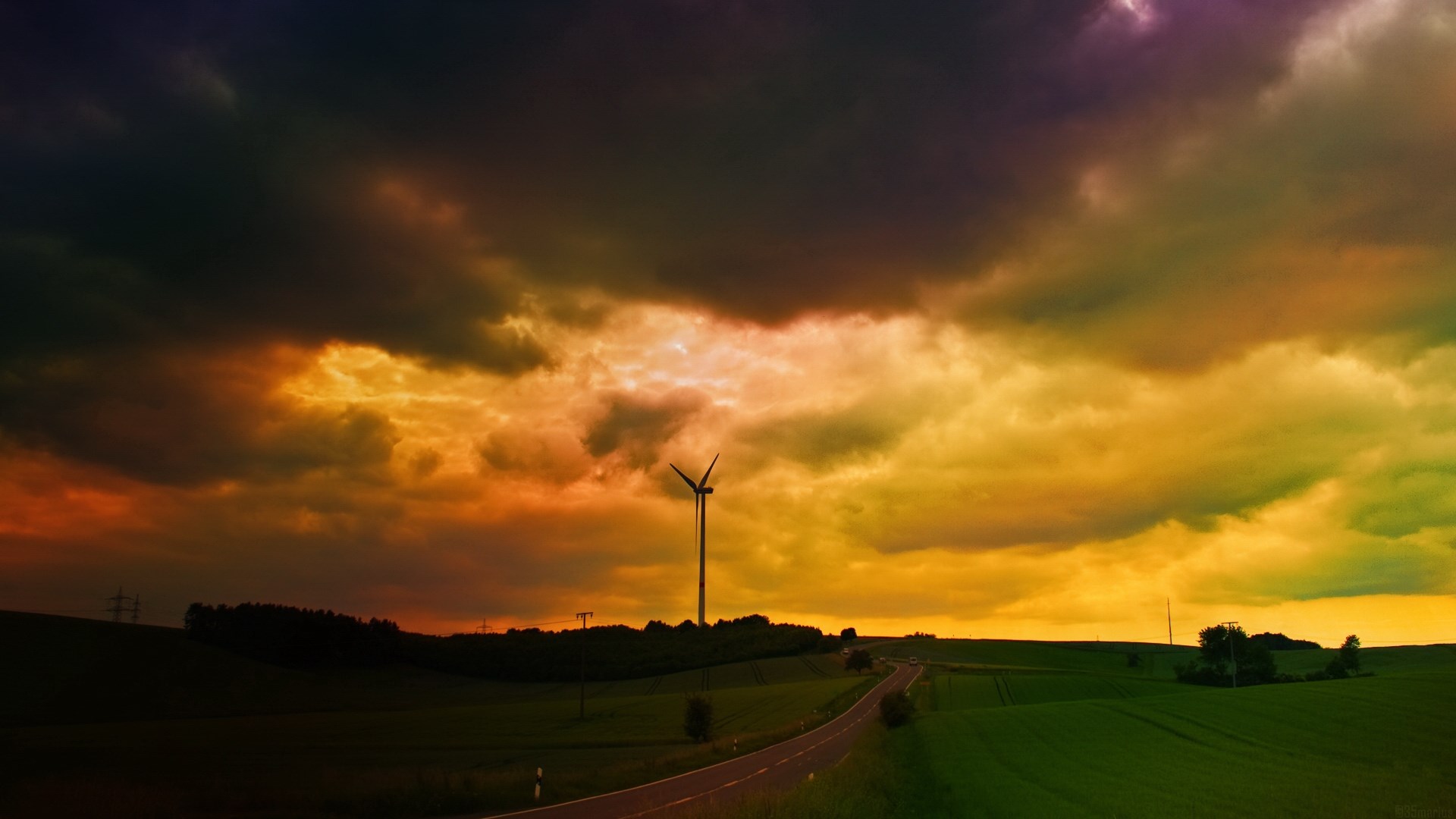 Wind turbine in a stormy, colorful sky over a rural landscape HD Wallpaper