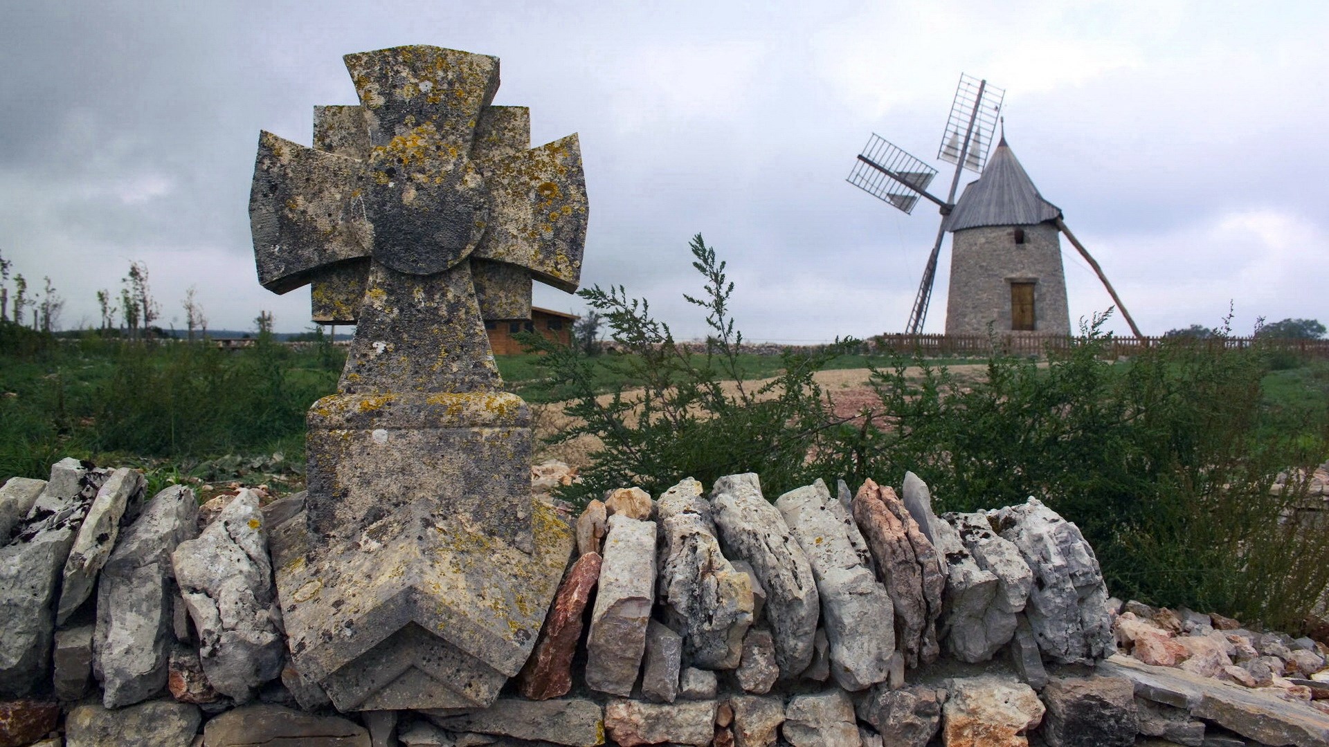 Stone cross and windmill in a field HD Wallpaper