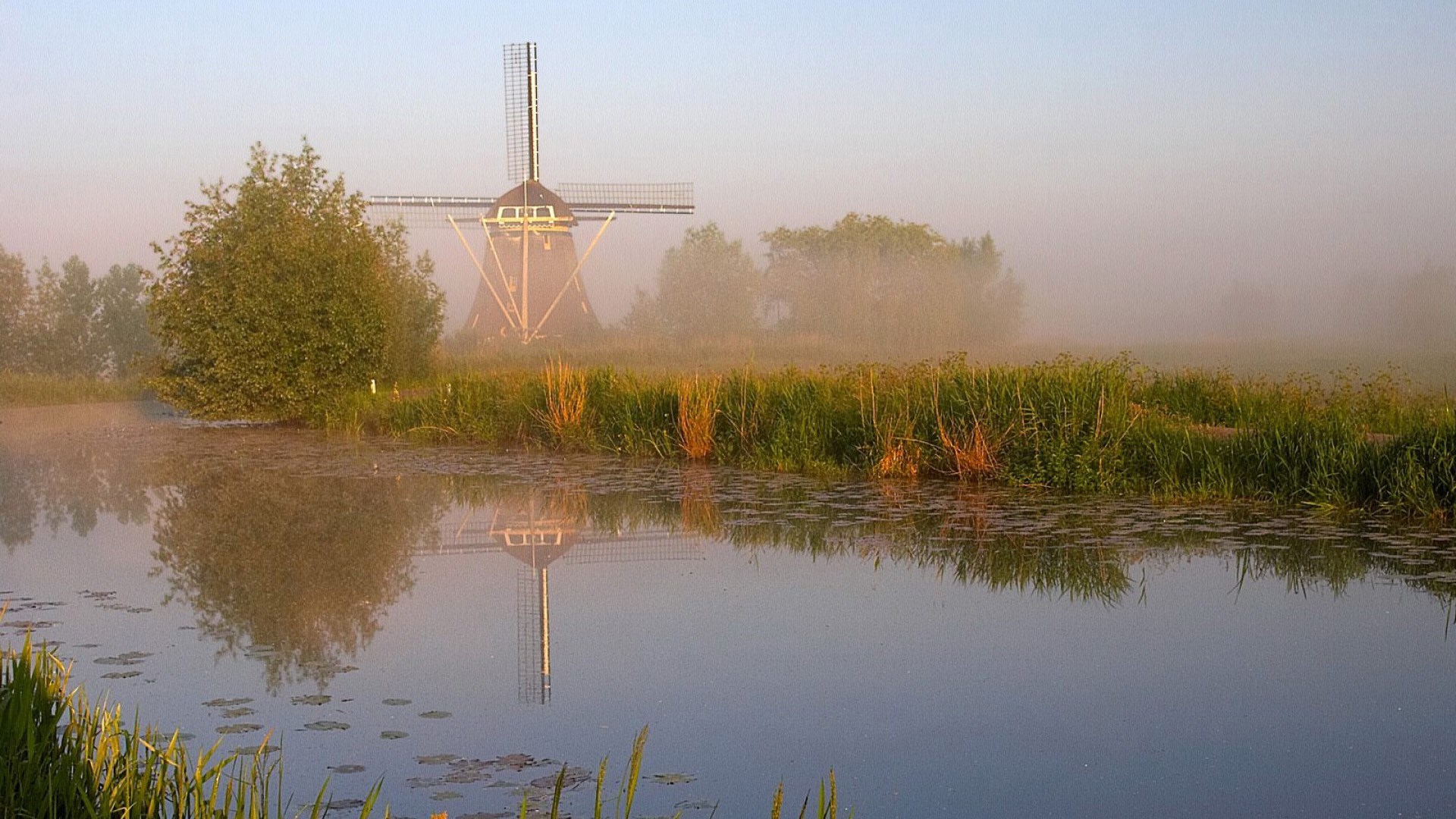 Windmill reflected in a misty canal at sunrise HD Wallpaper
