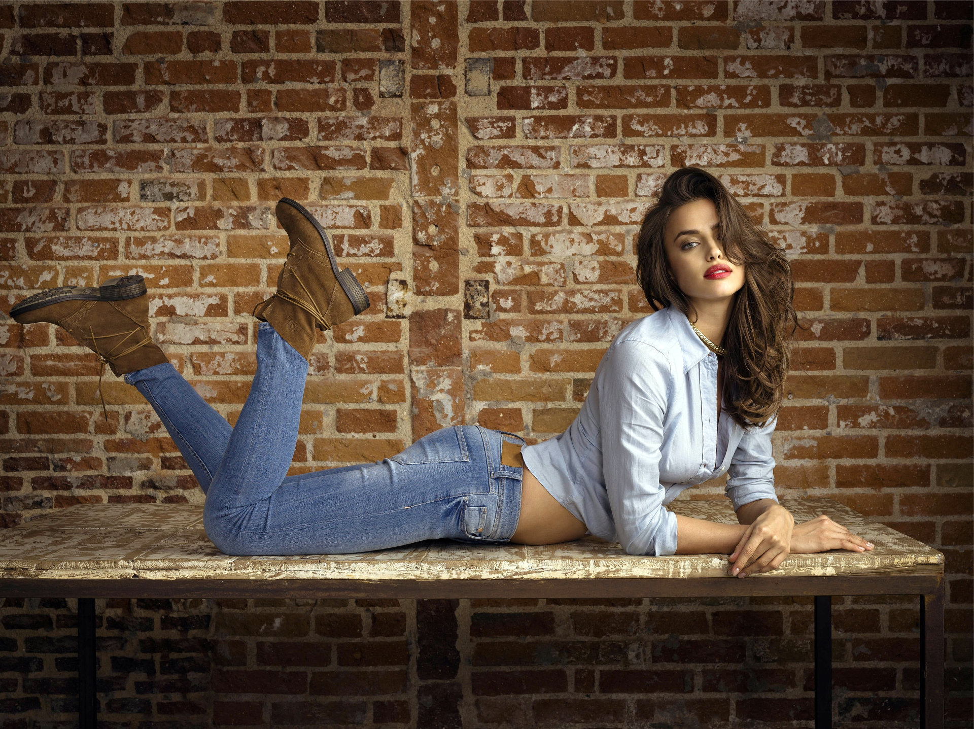 Irina Shayk lying on a table in front of a brick wall HD Wallpaper