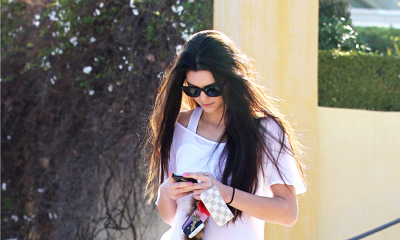 Kendall Jenner using her phone outdoors HD Wallpaper