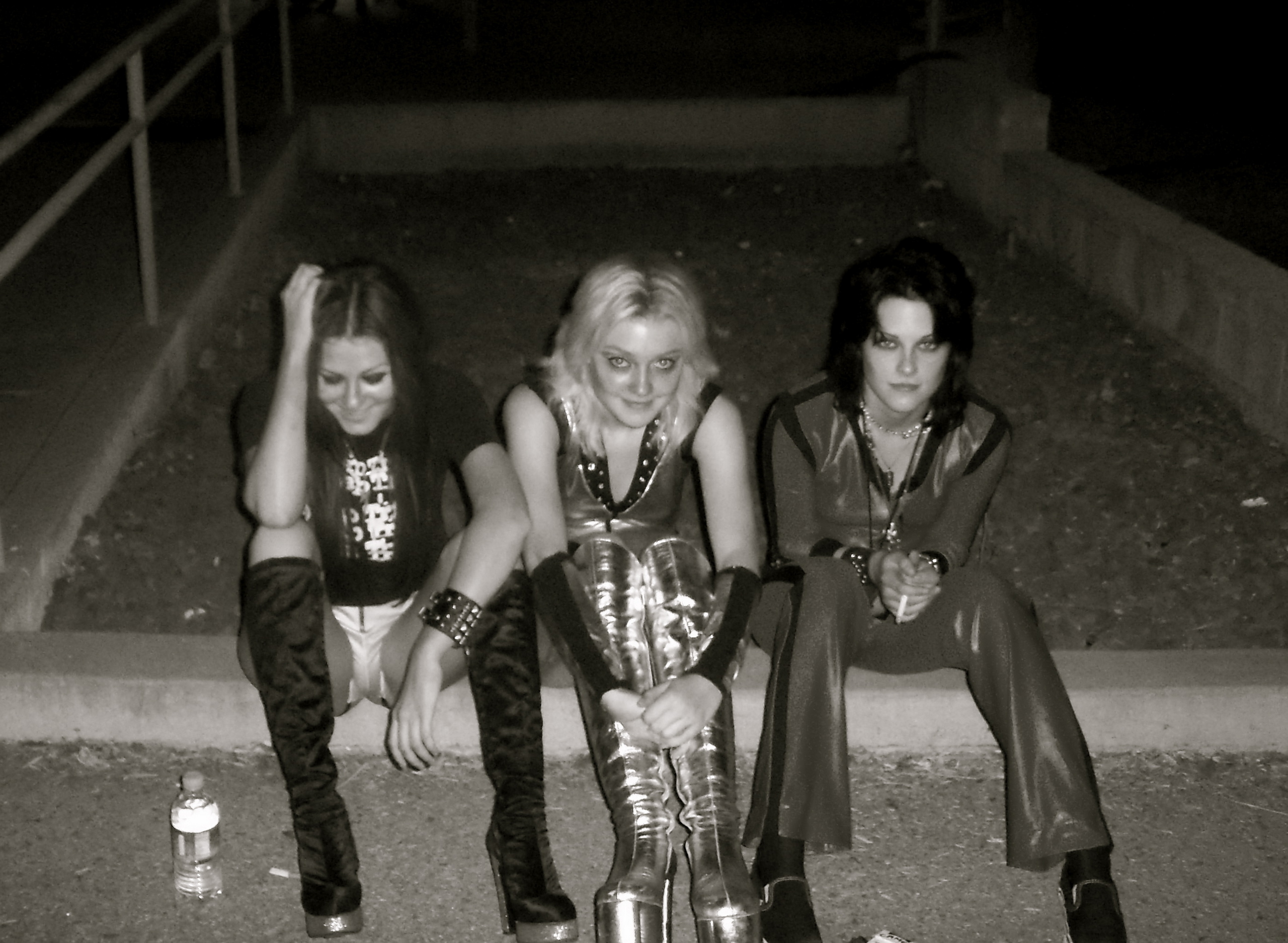 Three women in punk rock attire sitting outdoors at night HD Wallpaper