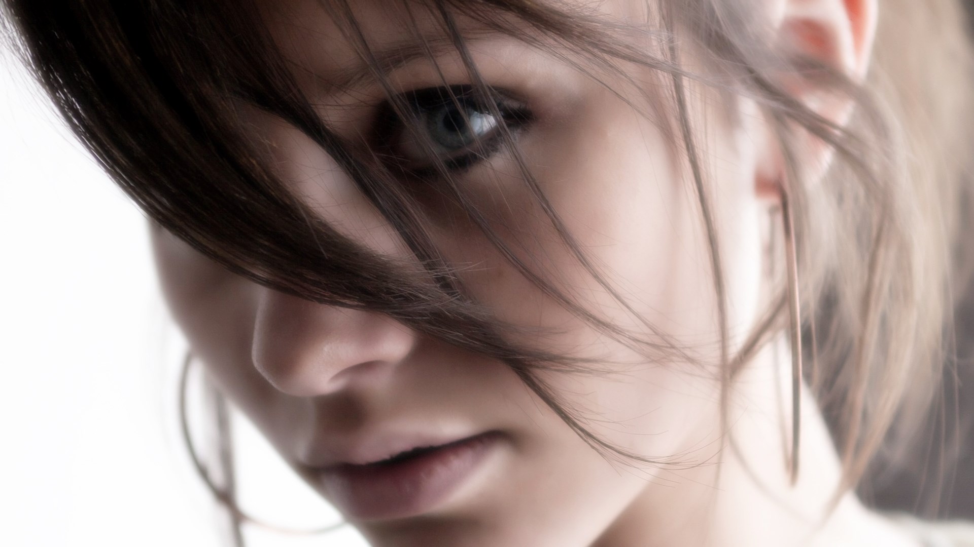 Close-up of a young woman's face with hair obscuring her eye HD Wallpaper