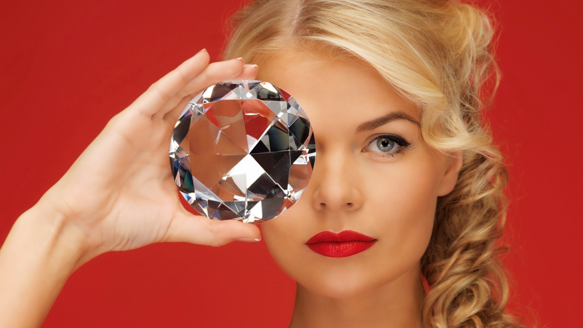 Woman holding a large diamond in front of her eye HD Wallpaper