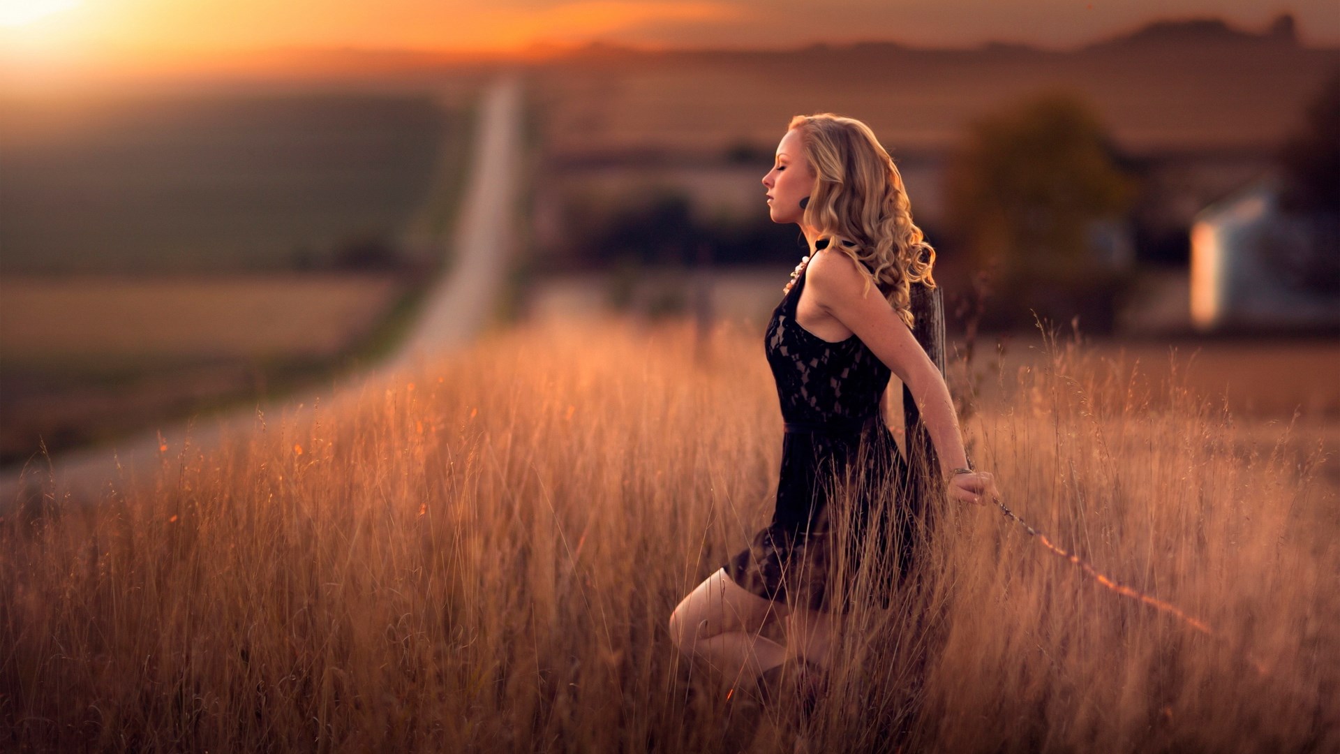Woman in black dress in a field at sunset HD Wallpaper