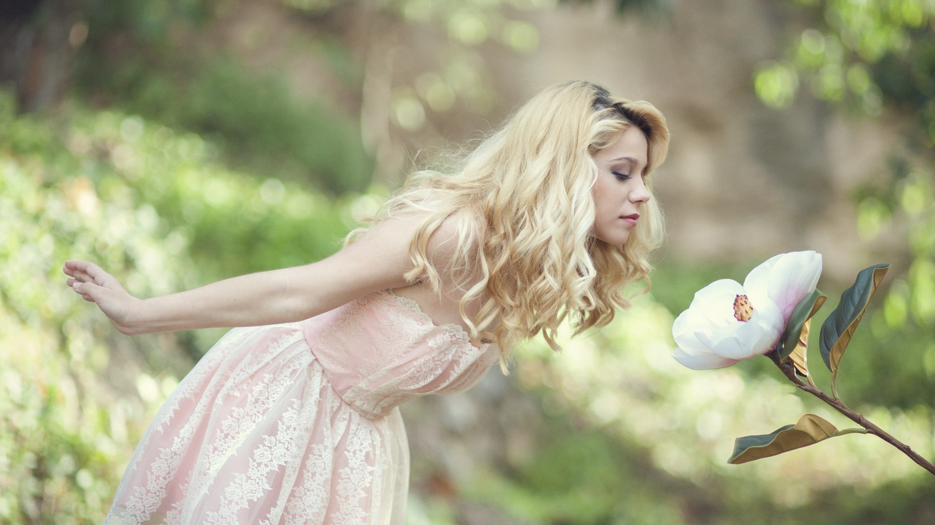 Woman in pink dress smelling a large white flower HD Wallpaper