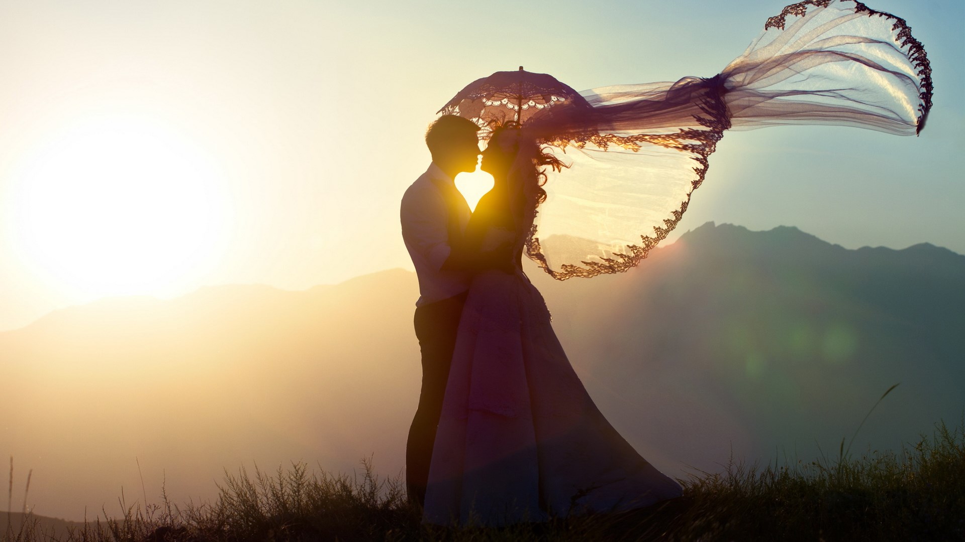 Couple kissing under an umbrella at sunset HD Wallpaper