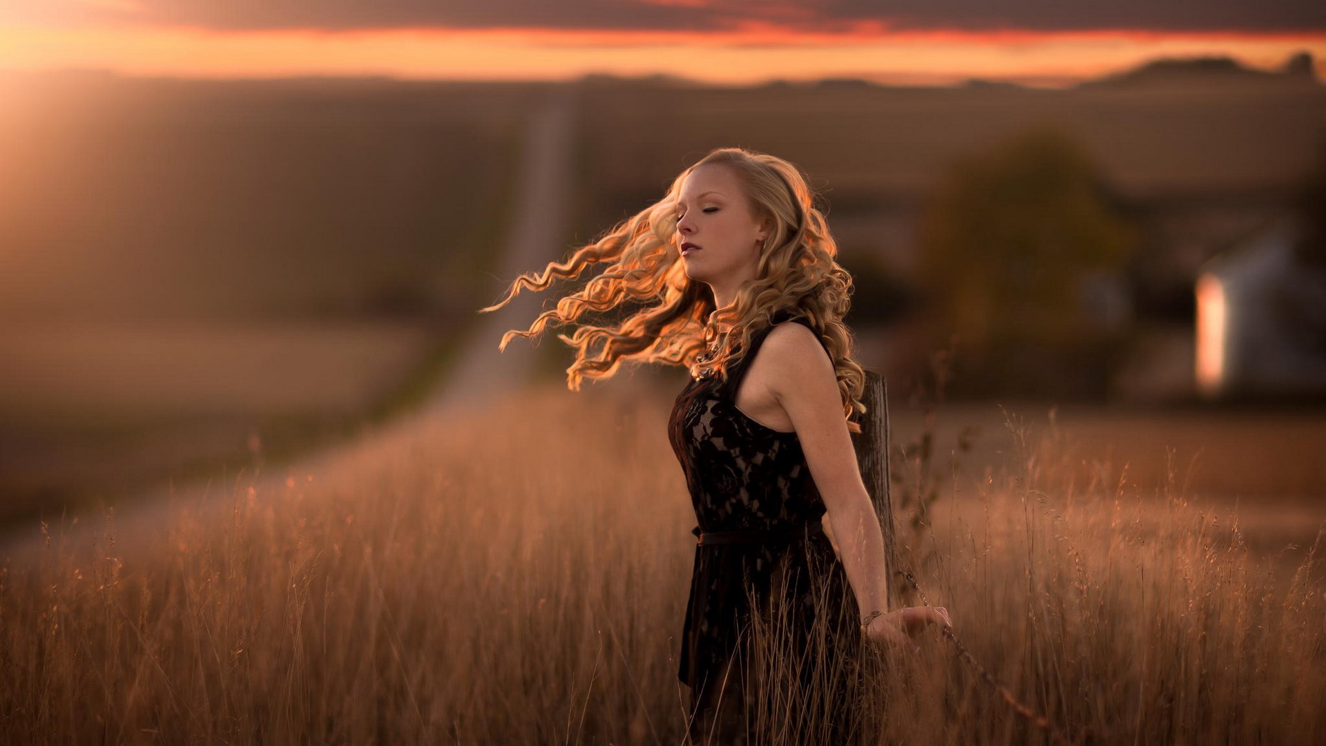 Woman with curly hair in a field at sunset HD Wallpaper