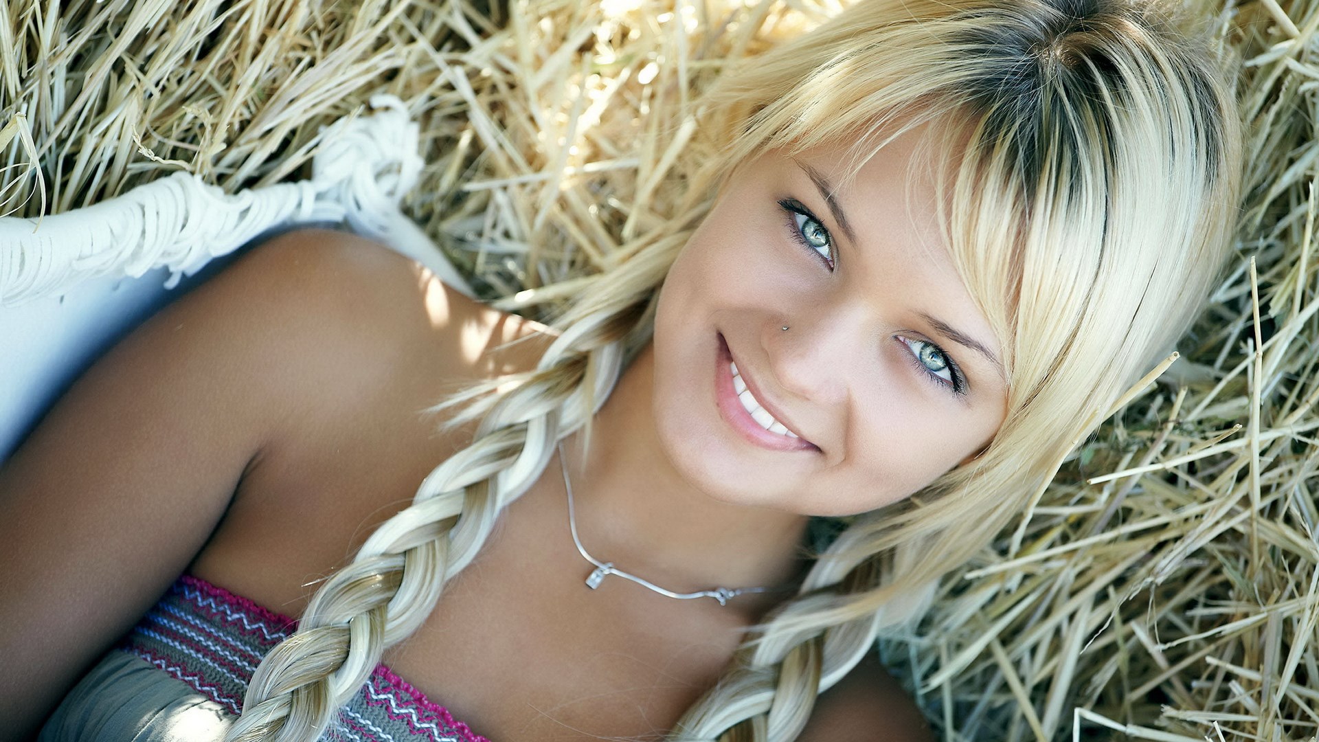Blonde woman with braided hair lying in hay HD Wallpaper