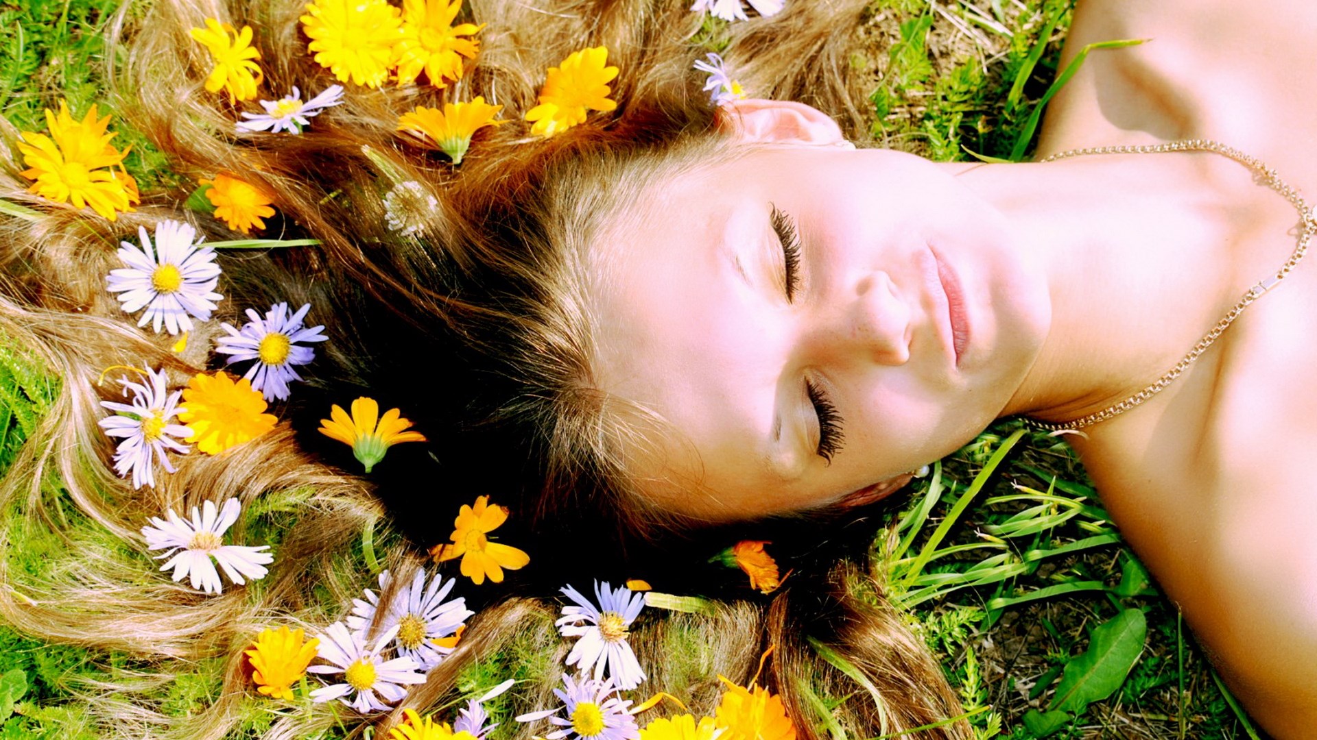 Woman with flowers in her hair lying on grass HD Wallpaper
