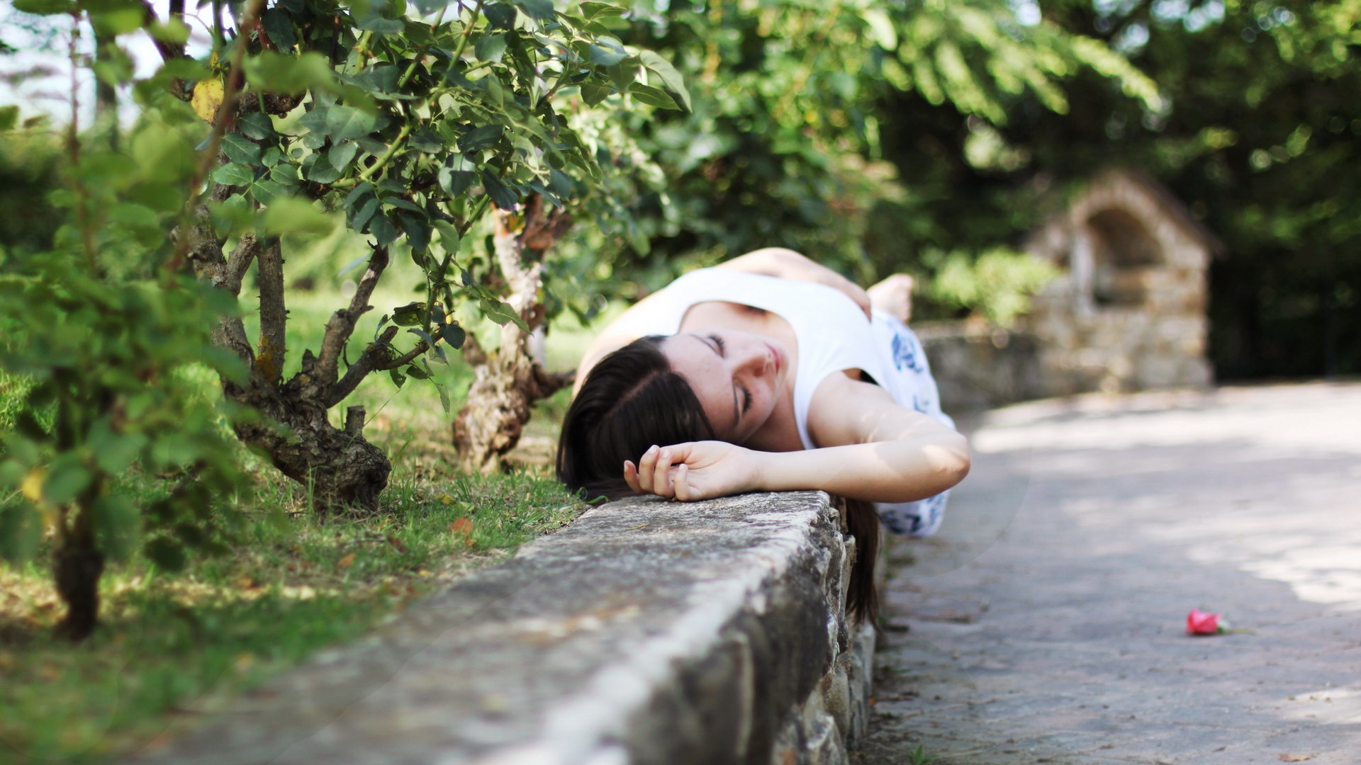 Woman lying on a stone wall in a garden HD Wallpaper