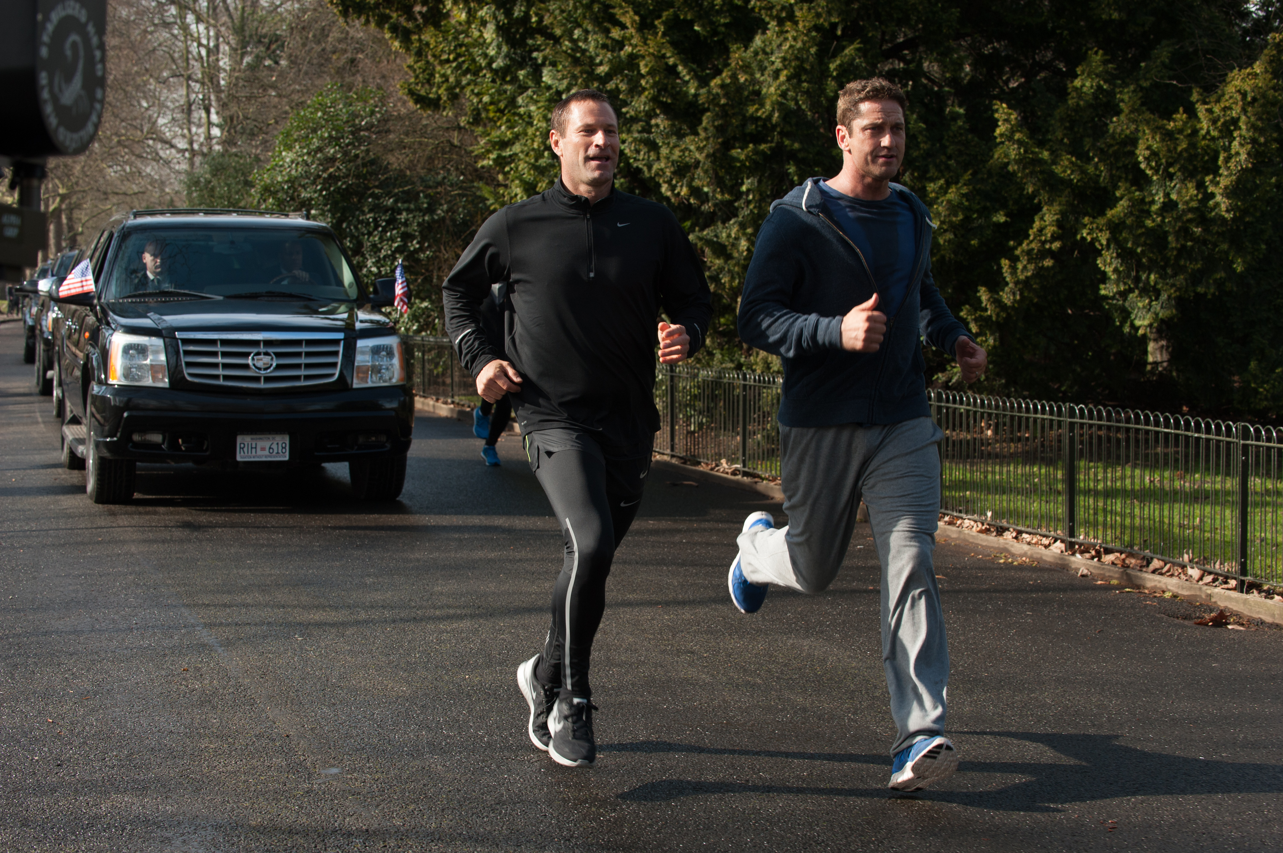 Gerard Butler running with a man next to a motorcade HD Wallpaper