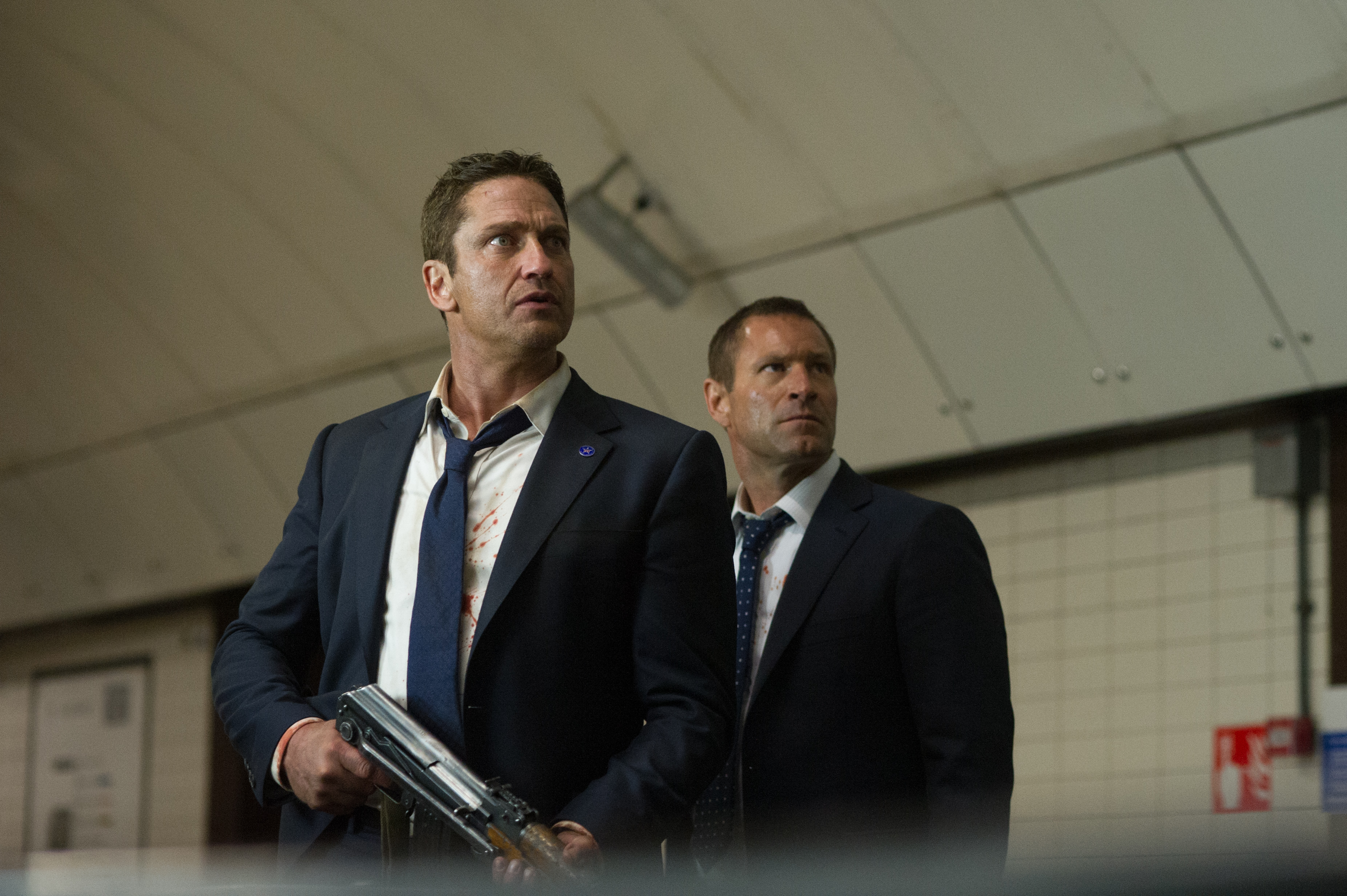 Gerard Butler in a dark suit holding a rifle HD Wallpaper