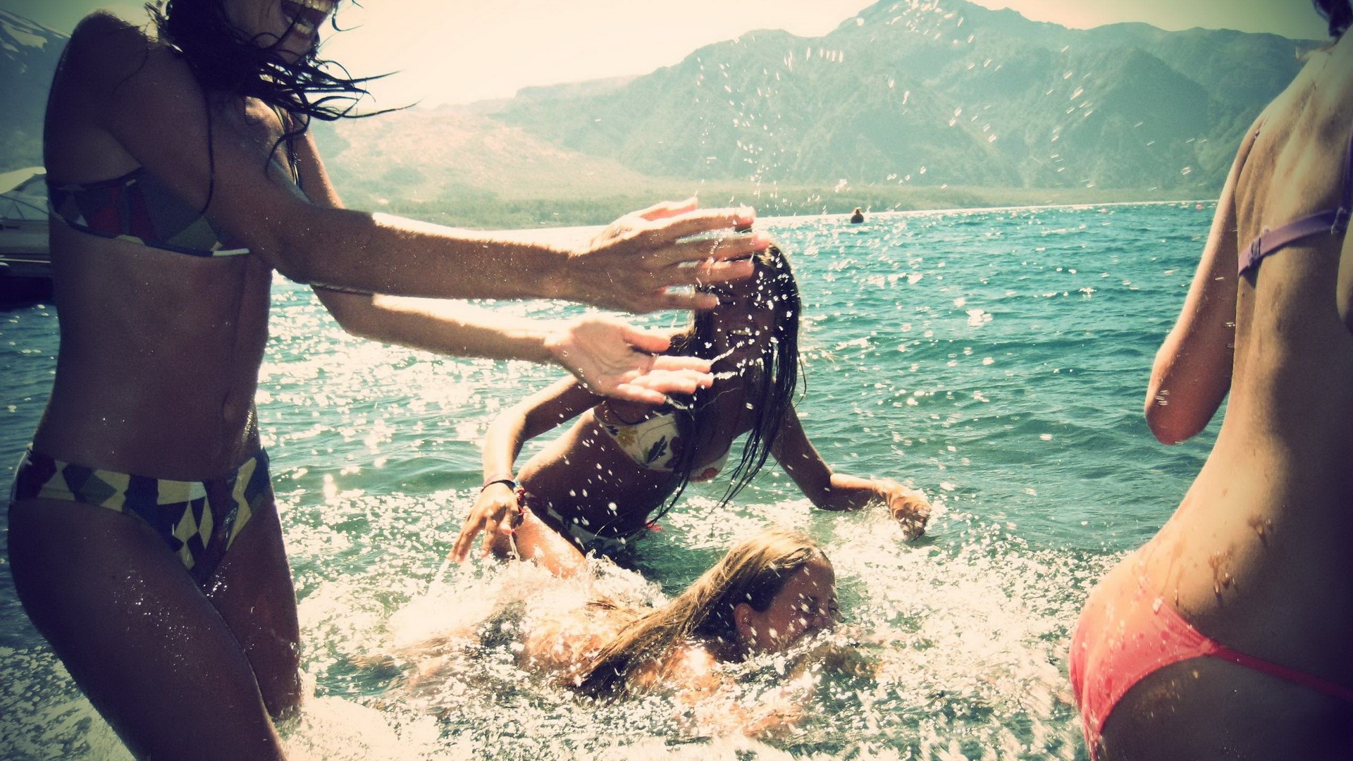 Women splashing water in a lake with mountains HD Wallpaper