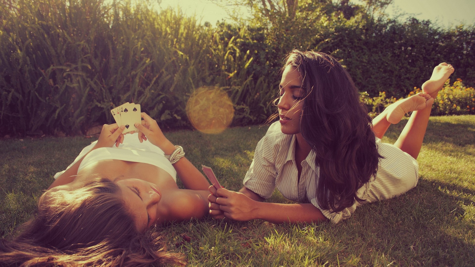 Two women playing cards on grass HD Wallpaper
