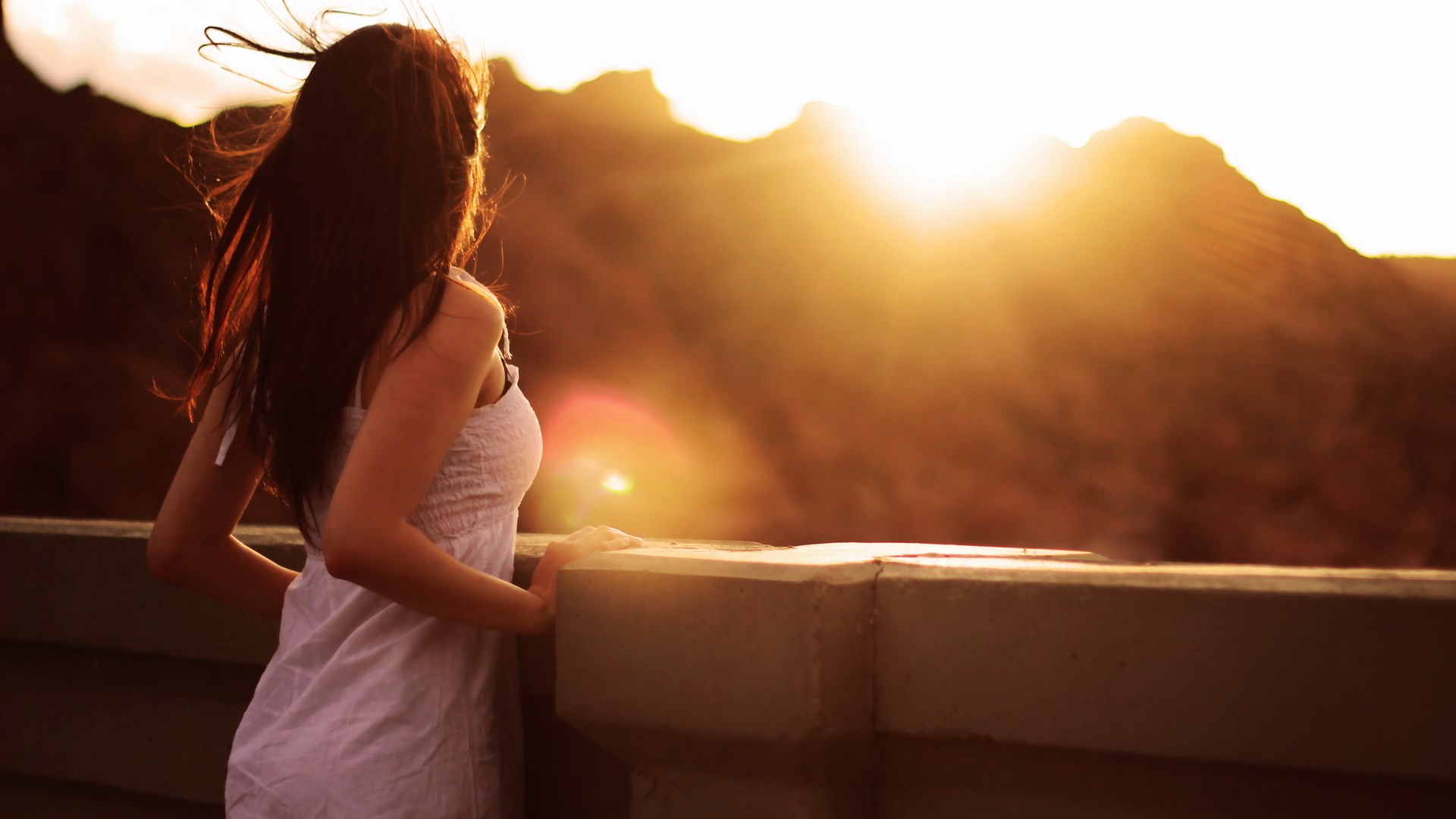Woman in white dress looking at sunset over mountains HD Wallpaper