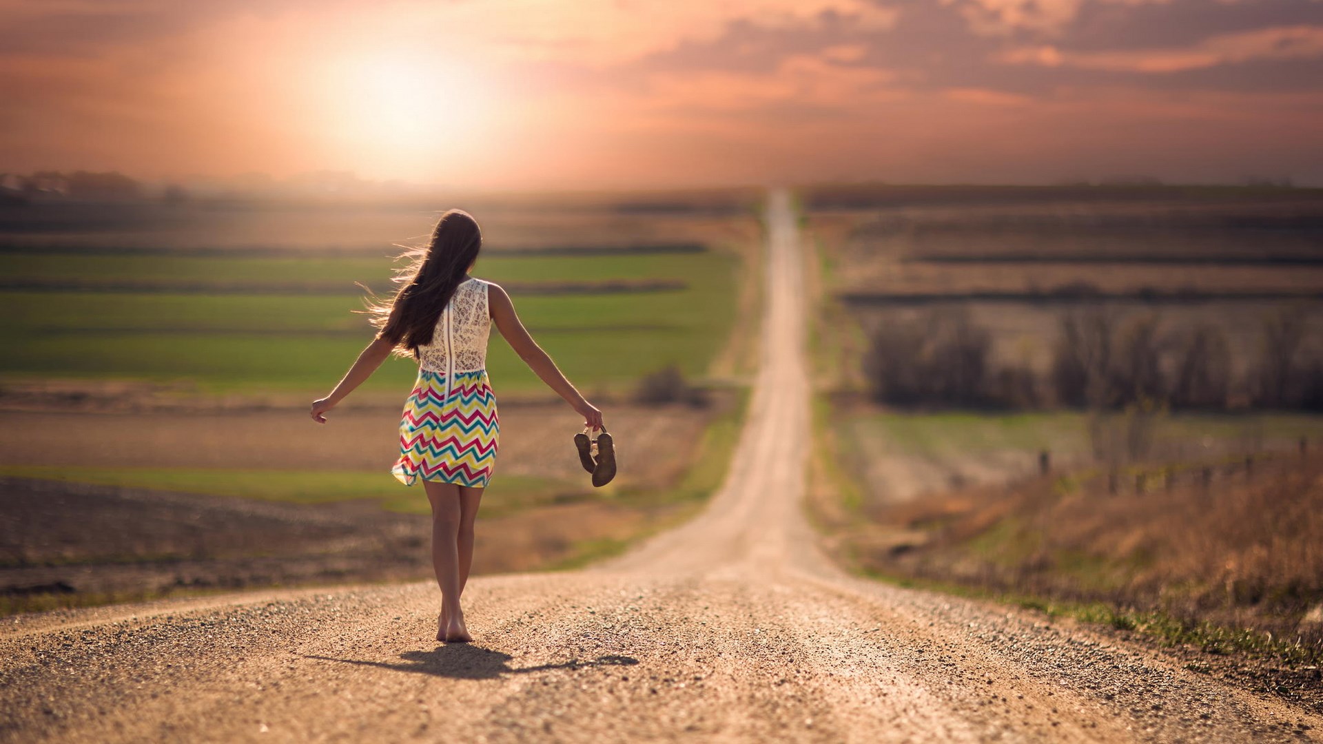 Woman walking on a dirt road at sunset HD Wallpaper