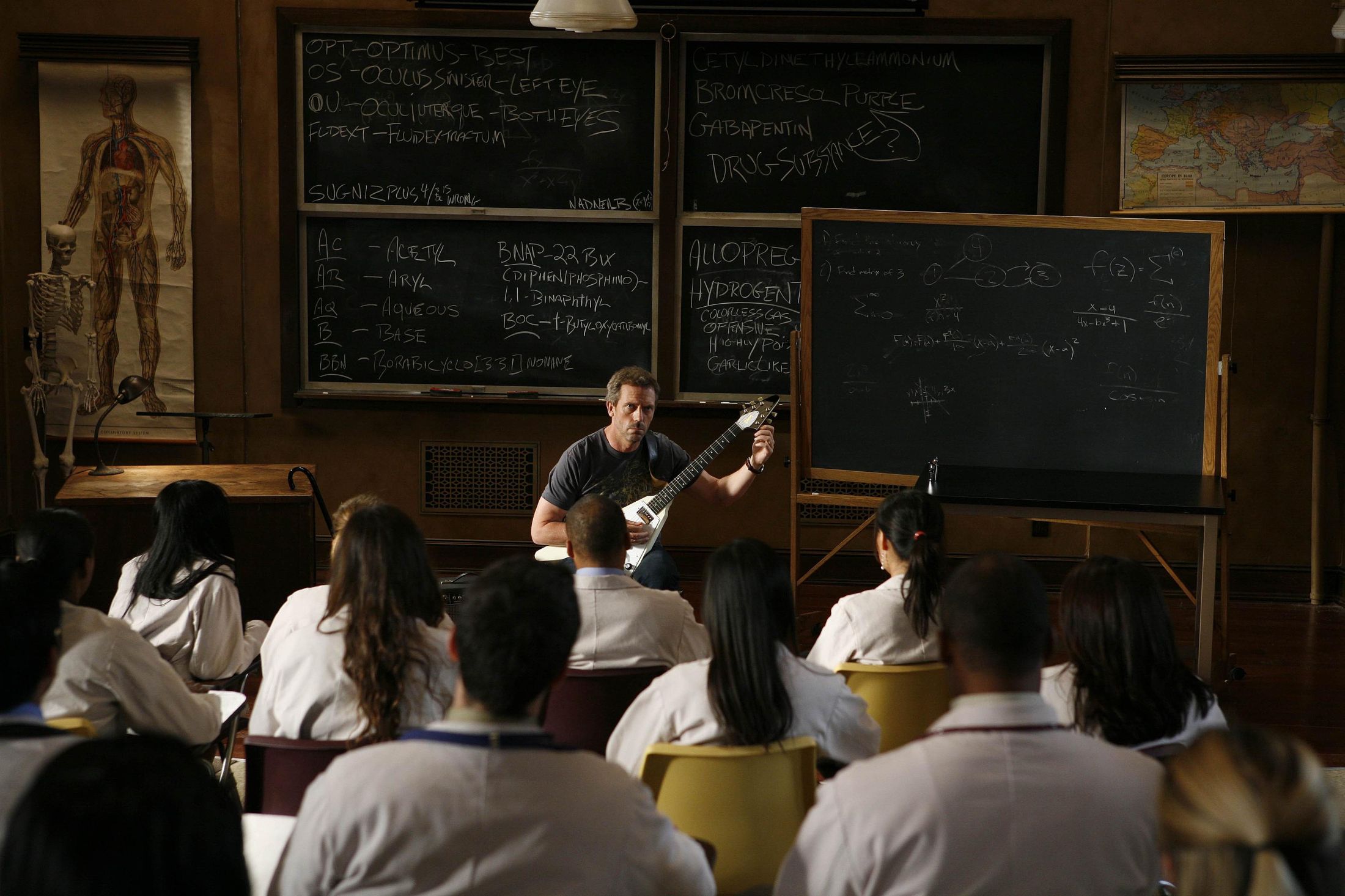 Hugh Laurie playing guitar in a classroom HD Wallpaper