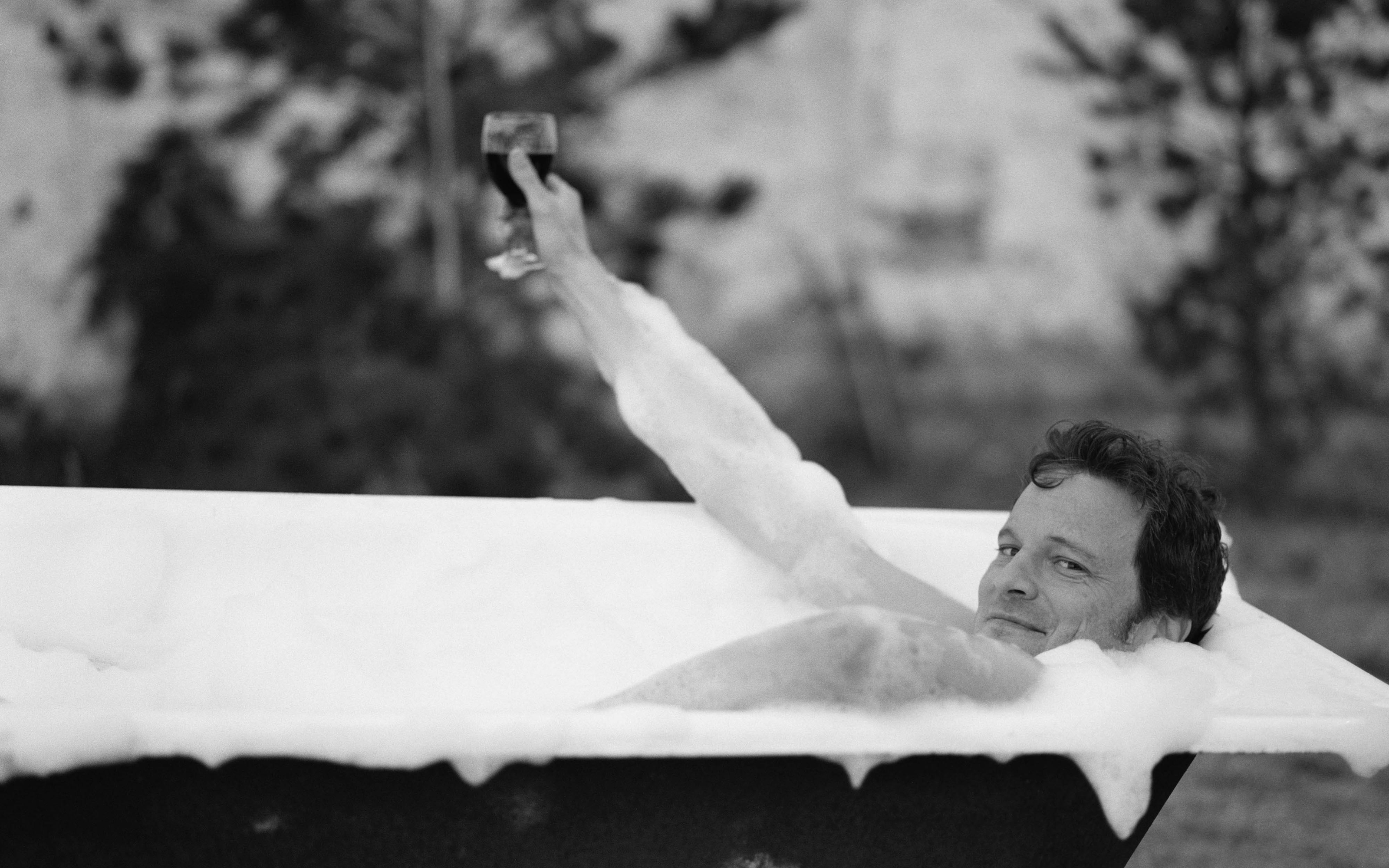 Colin Firth in a bubble bath holding a glass of wine HD Wallpaper