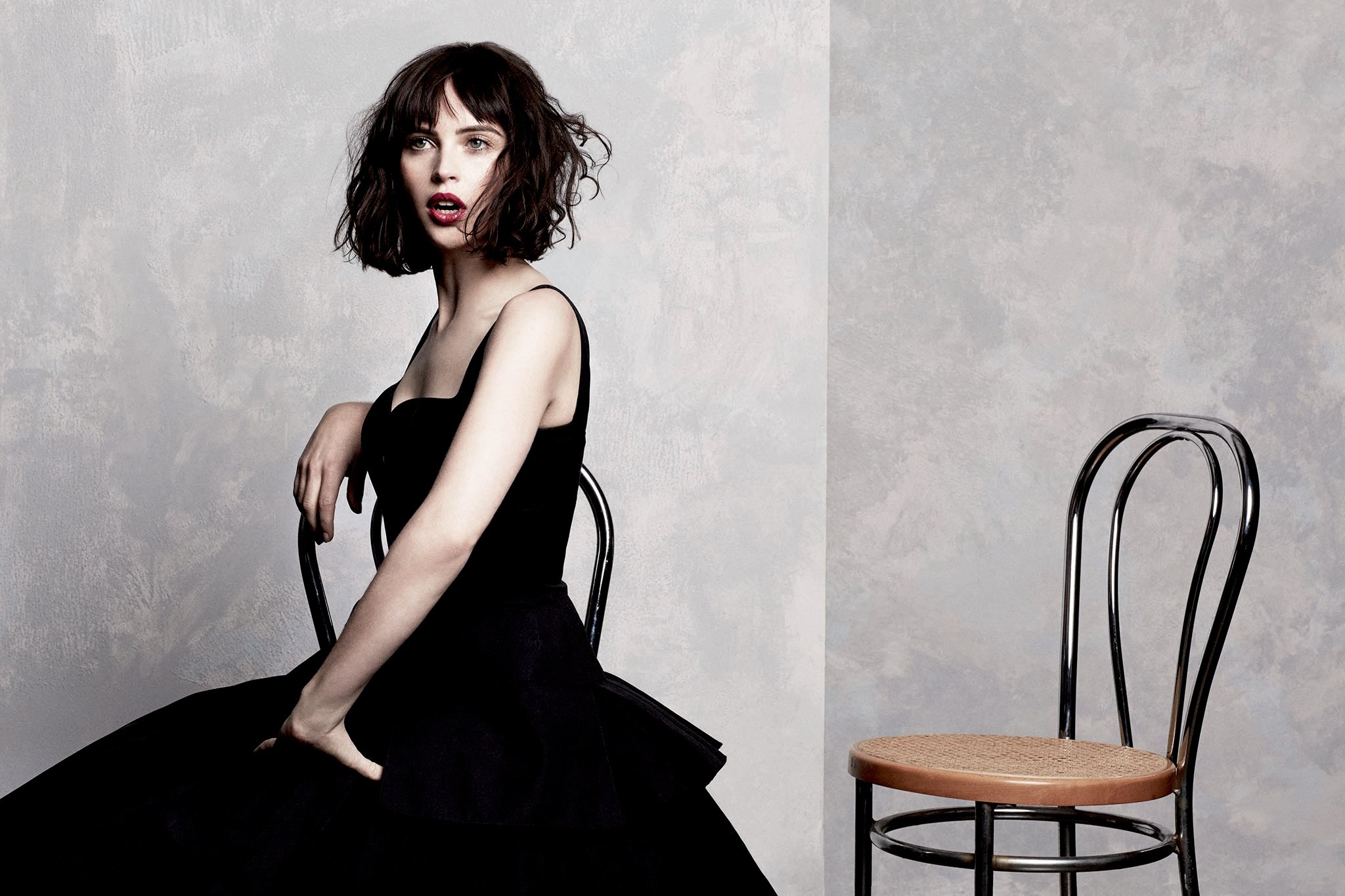 Felicity Jones in a black dress sitting on a chair HD Wallpaper