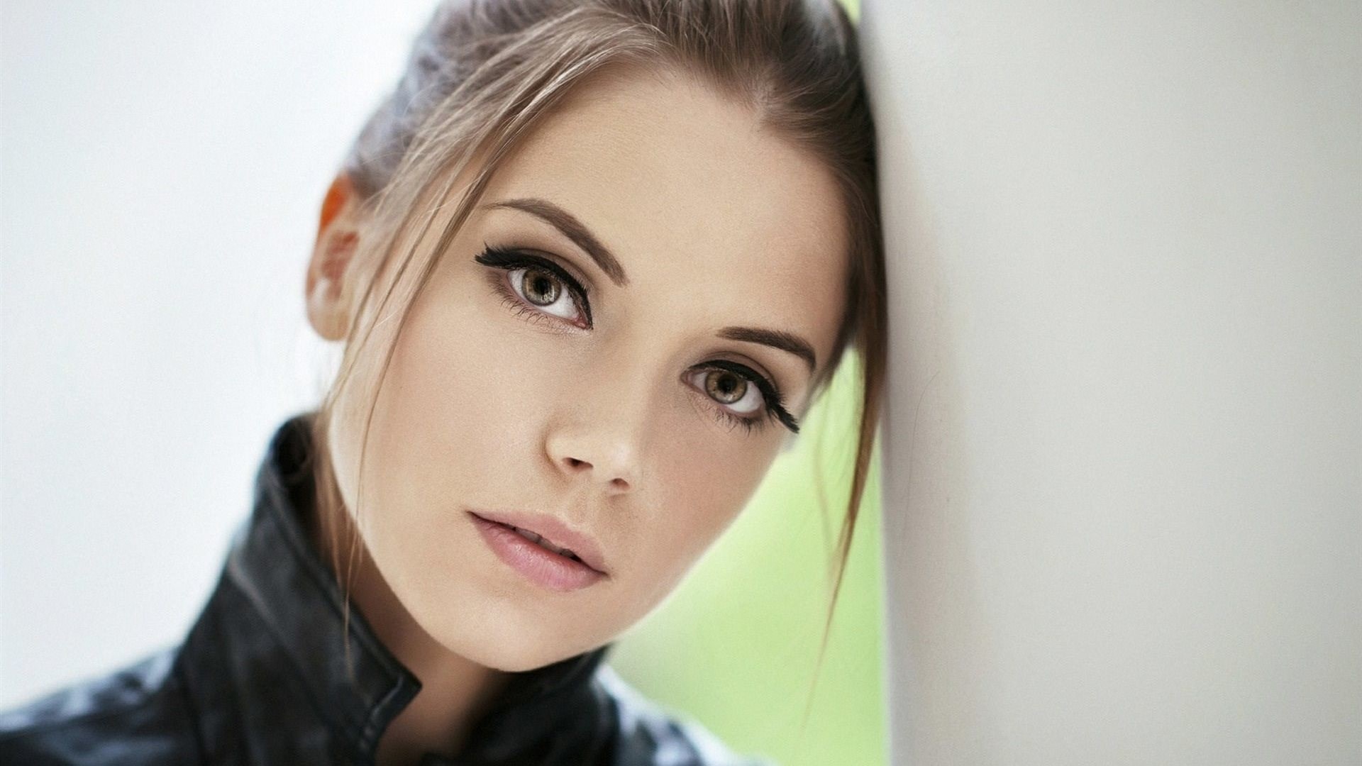 Woman with dramatic makeup leaning on a wall HD Wallpaper