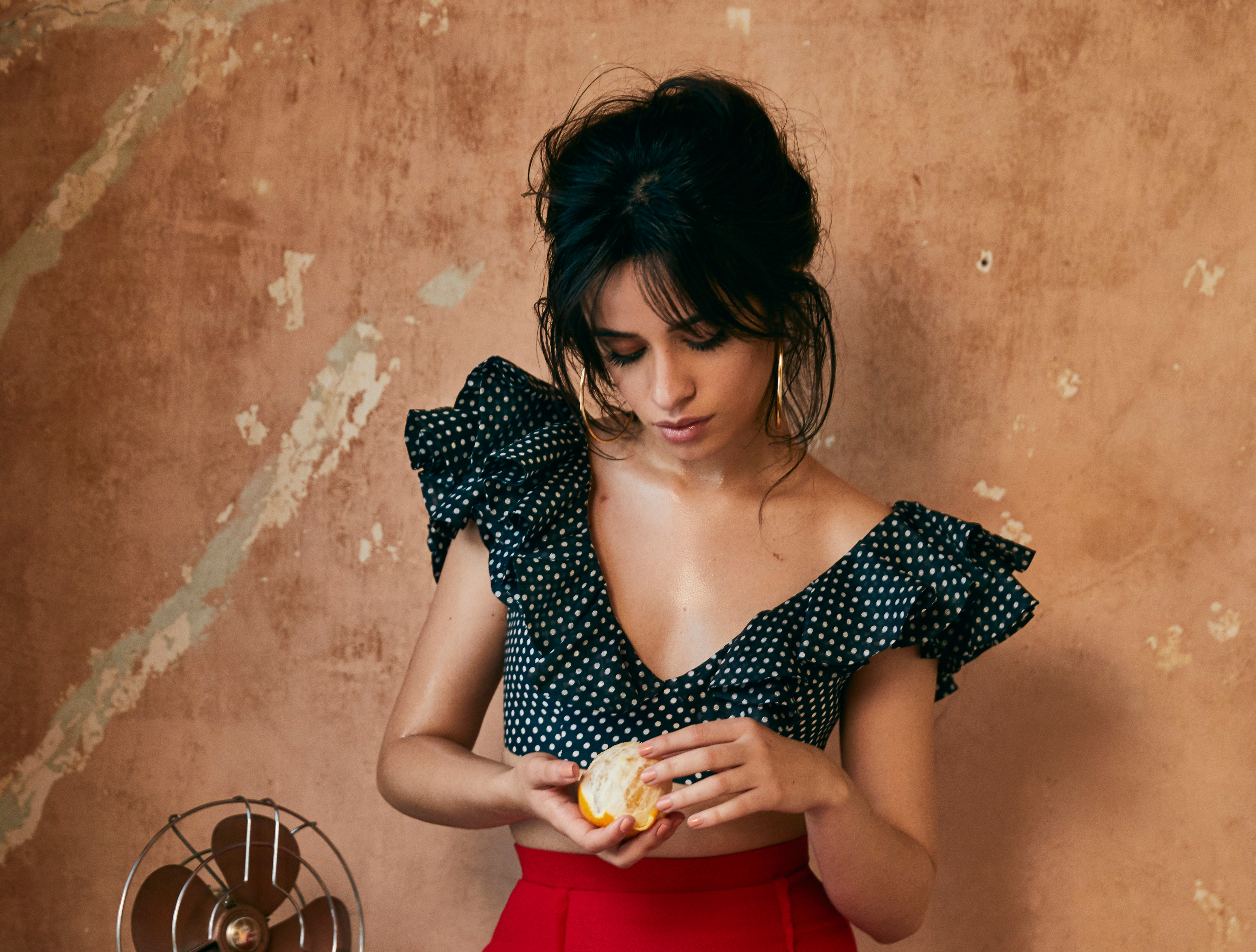 Camila Cabello holding an orange slice HD Wallpaper