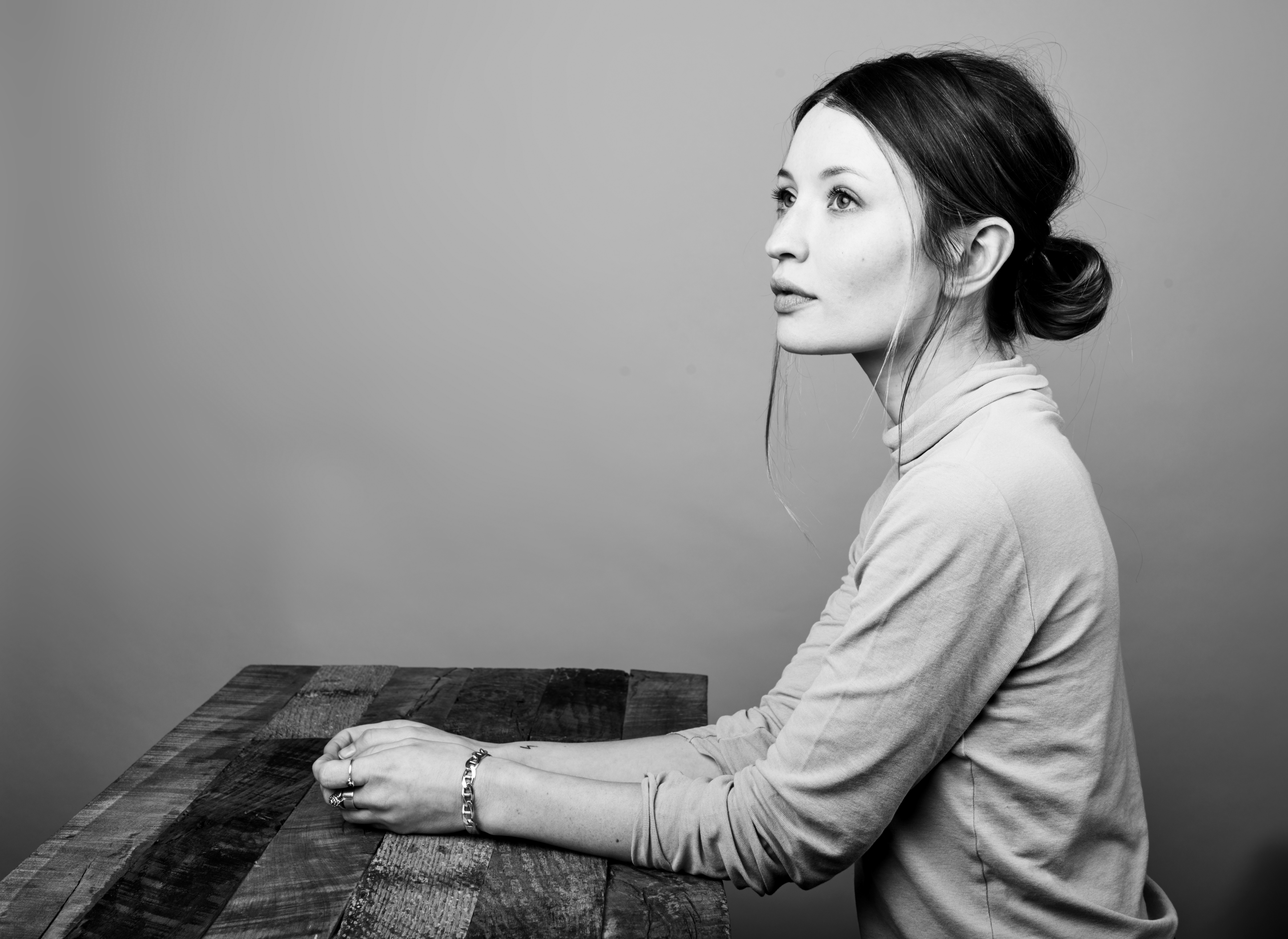 Emily Browning sitting at a wooden table HD Wallpaper