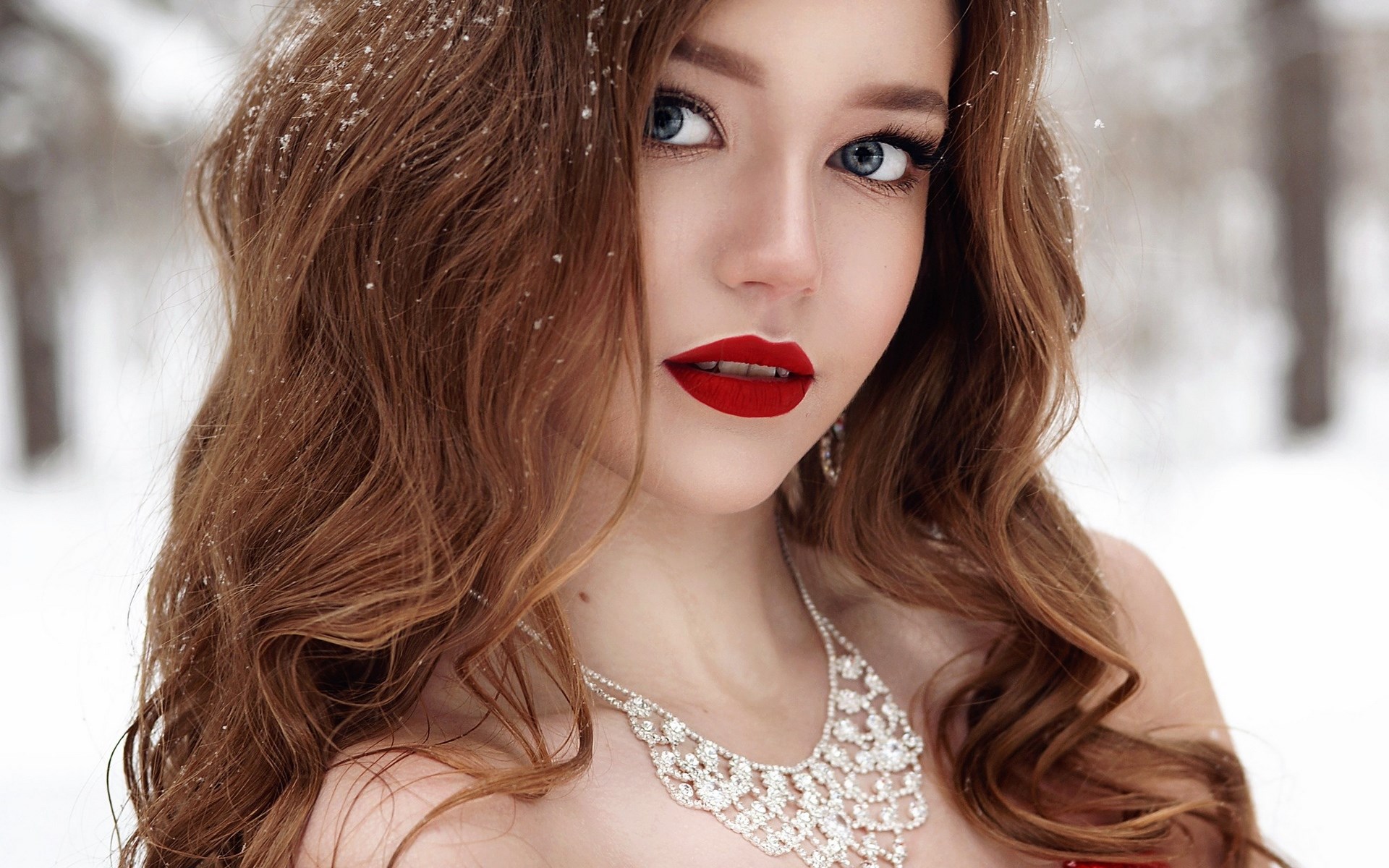 Woman with red lipstick and diamond necklace in snow HD Wallpaper