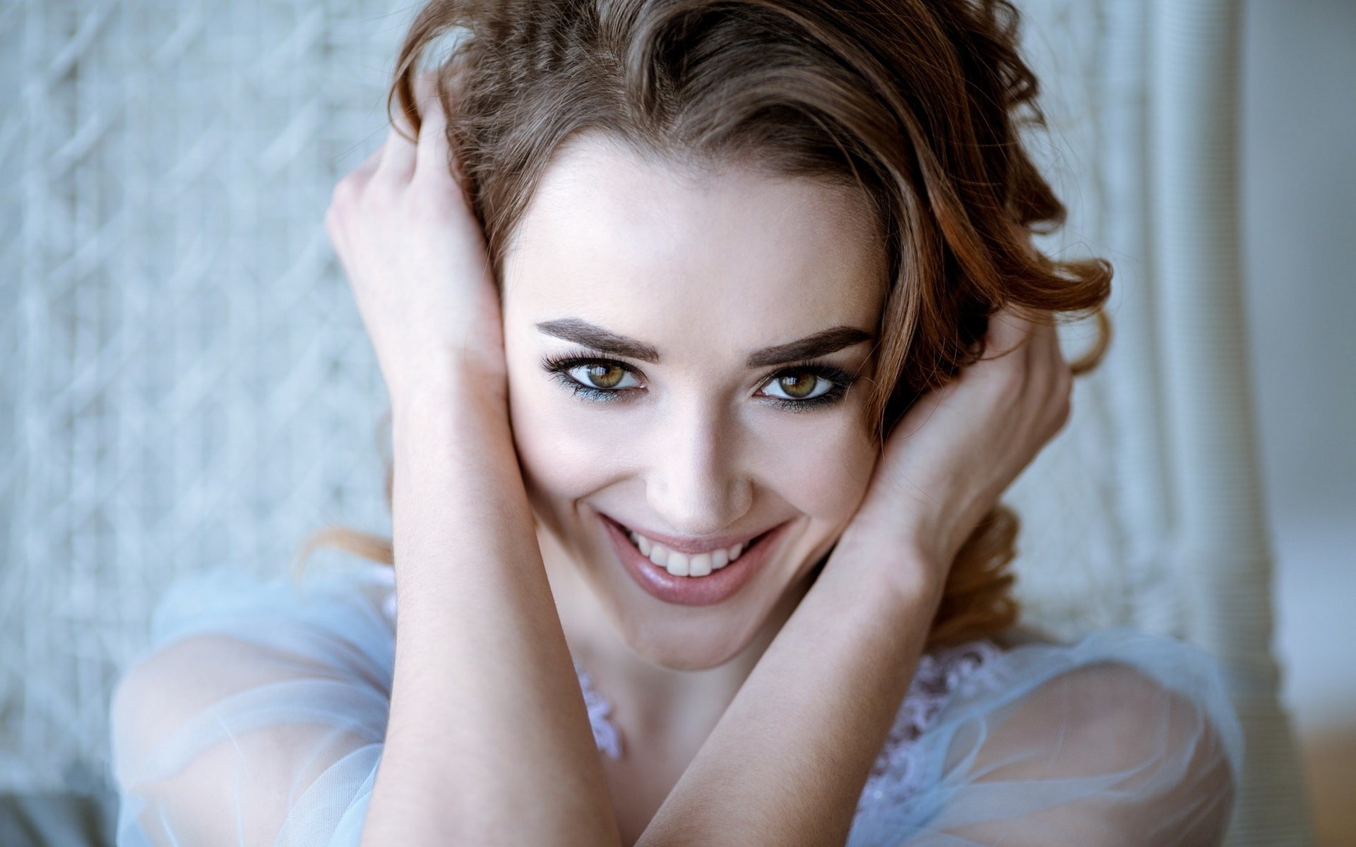 Woman with hands in hair smiling HD Wallpaper