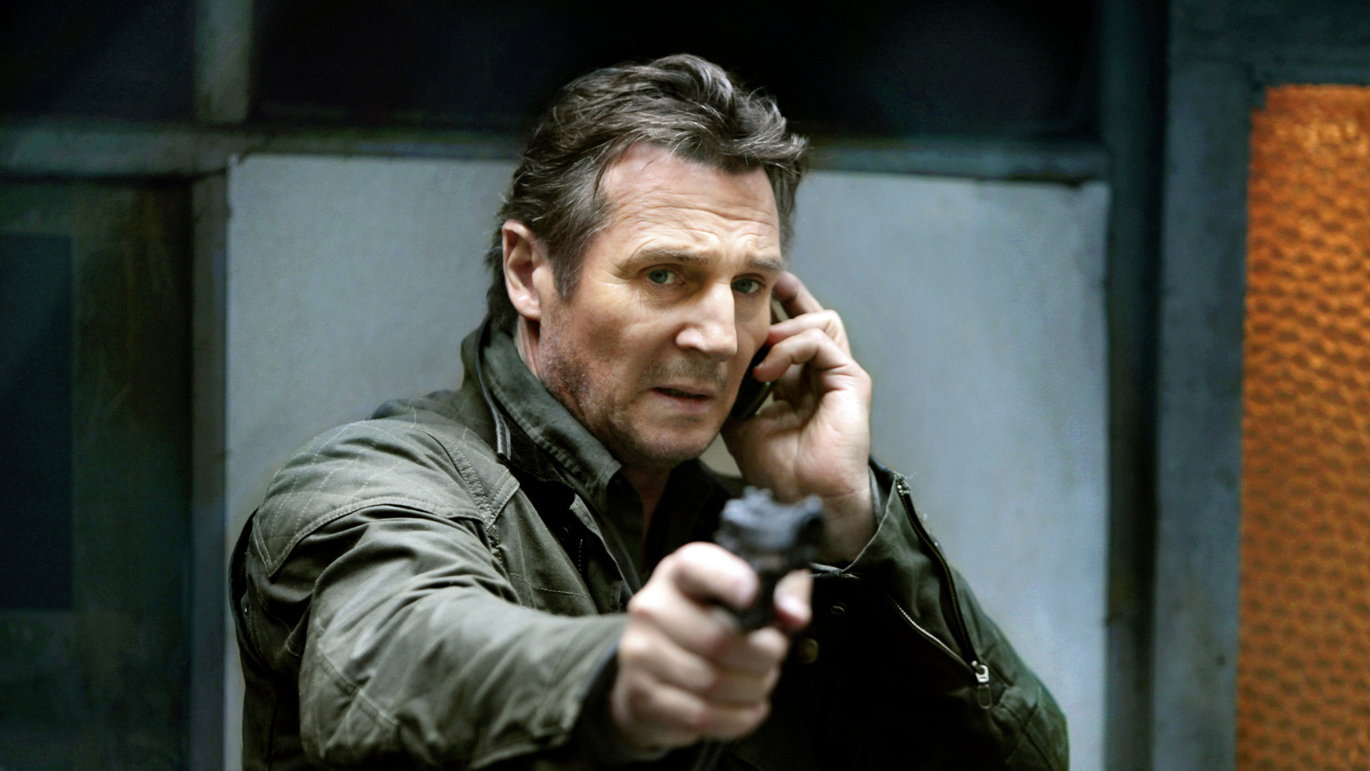 Liam Neeson holding a gun and phone HD Wallpaper