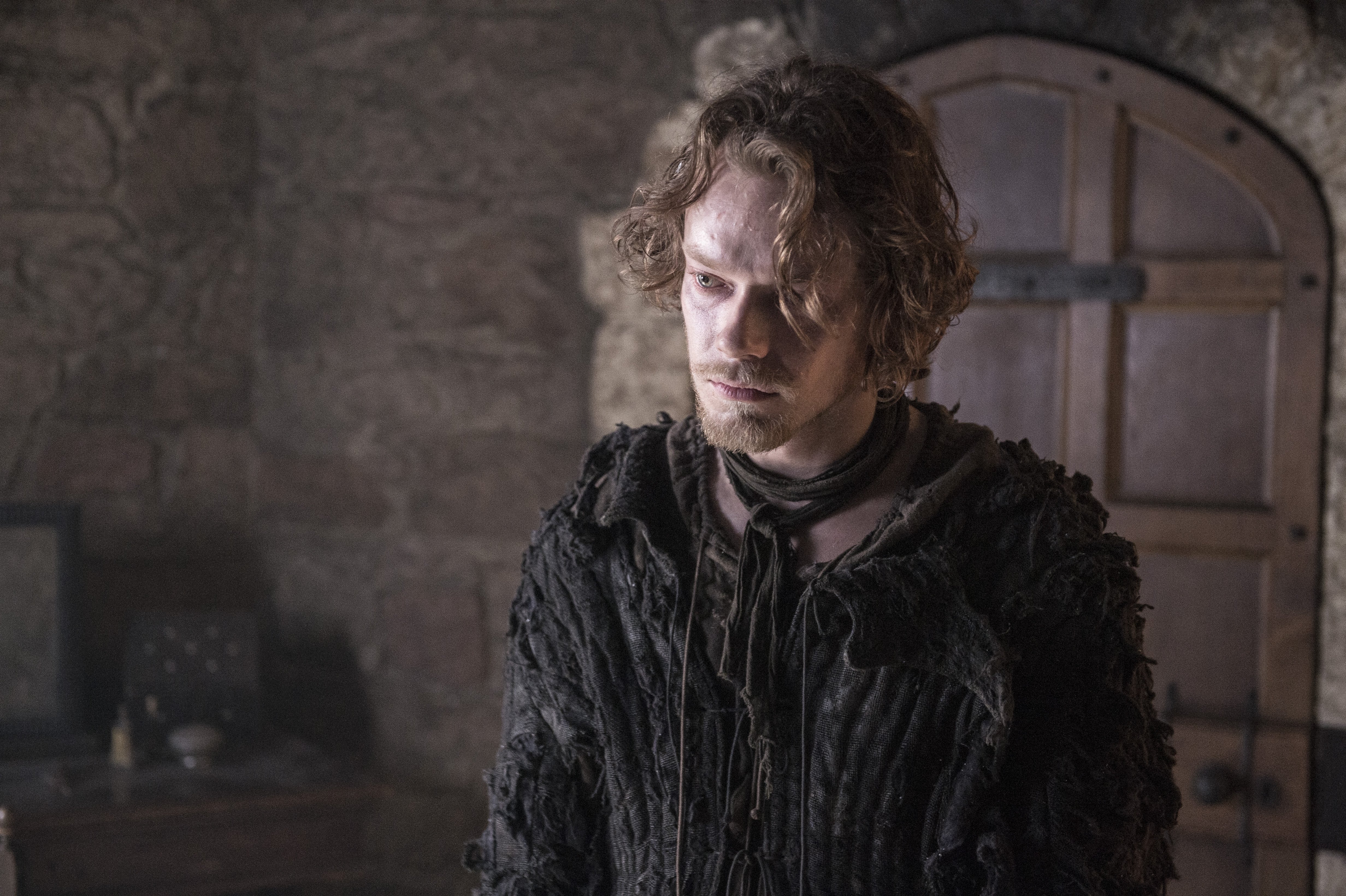 Alfie Allen in a dark, stone room HD Wallpaper
