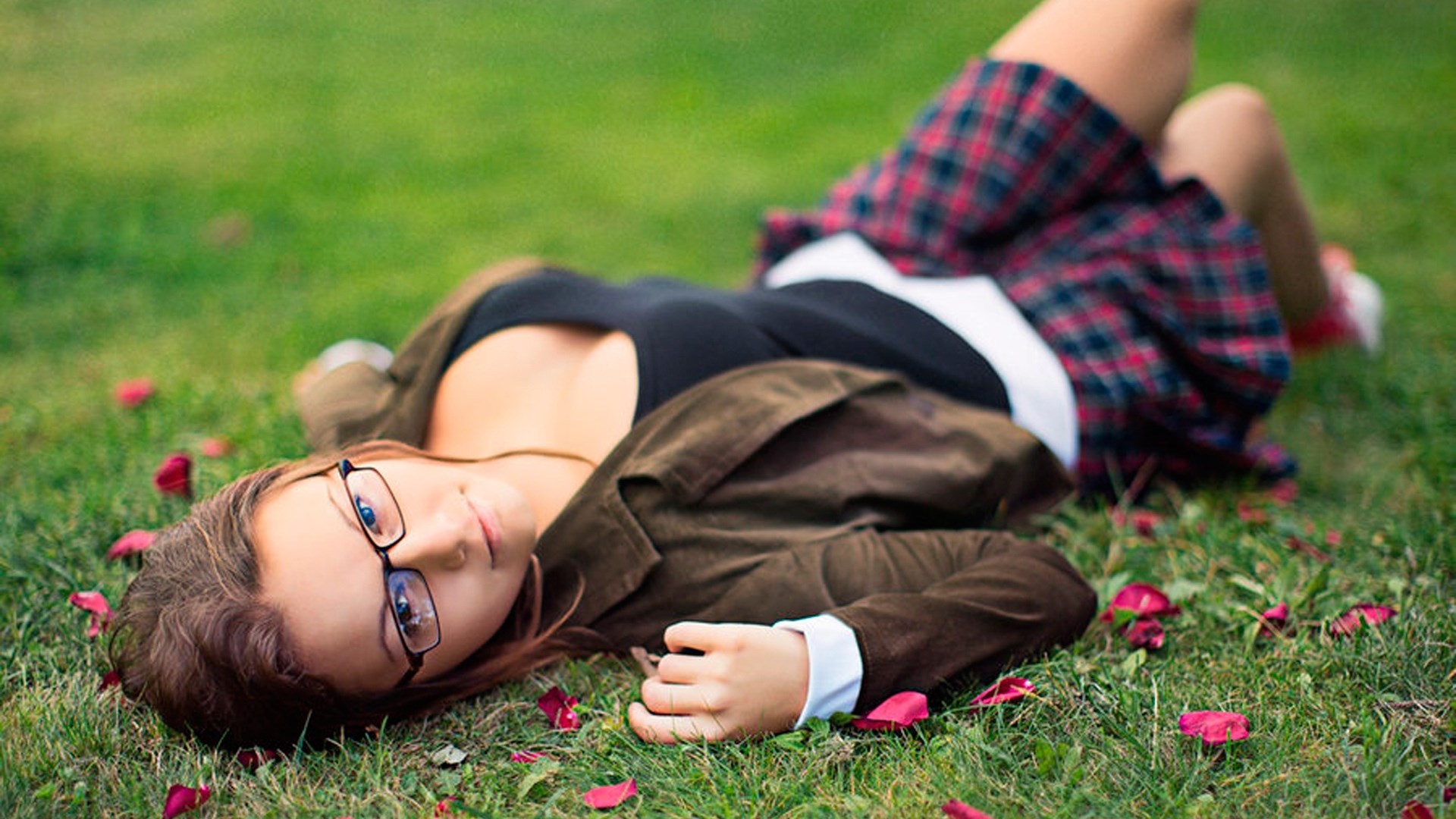 Woman in glasses lying on grass with rose petals HD Wallpaper