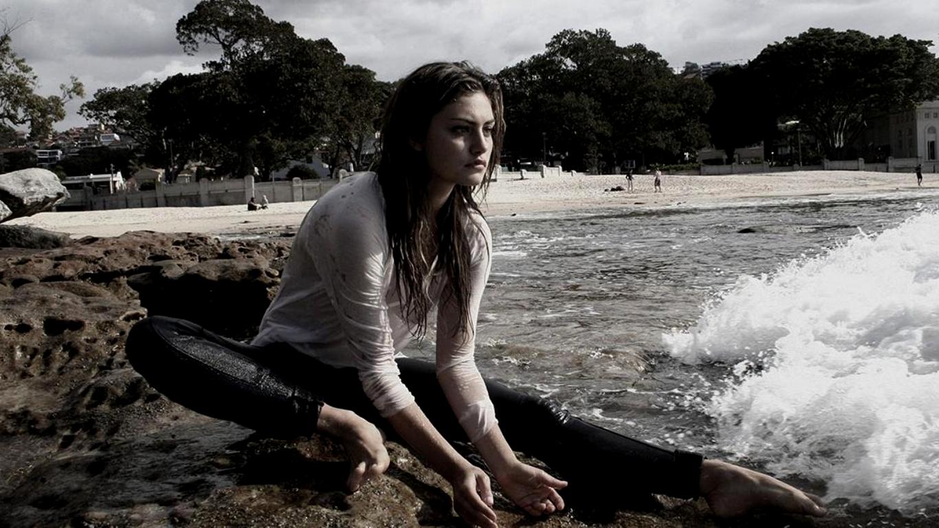 Phoebe Tonkin on a rocky beach with waves HD Wallpaper