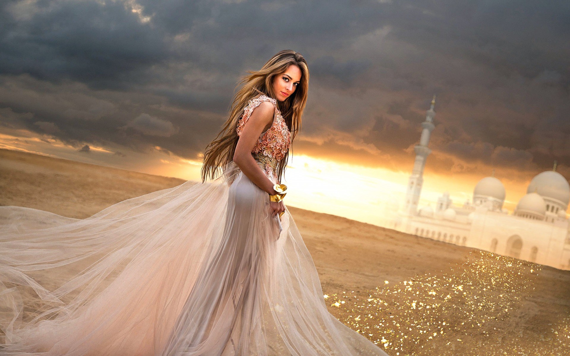 Woman in a flowing dress in a desert with a mosque HD Wallpaper