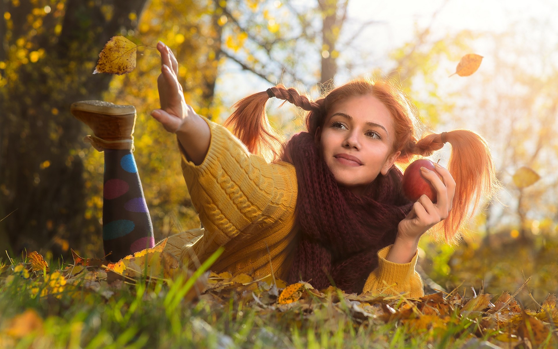 Girl with pigtails holding an apple in autumn leaves HD Wallpaper