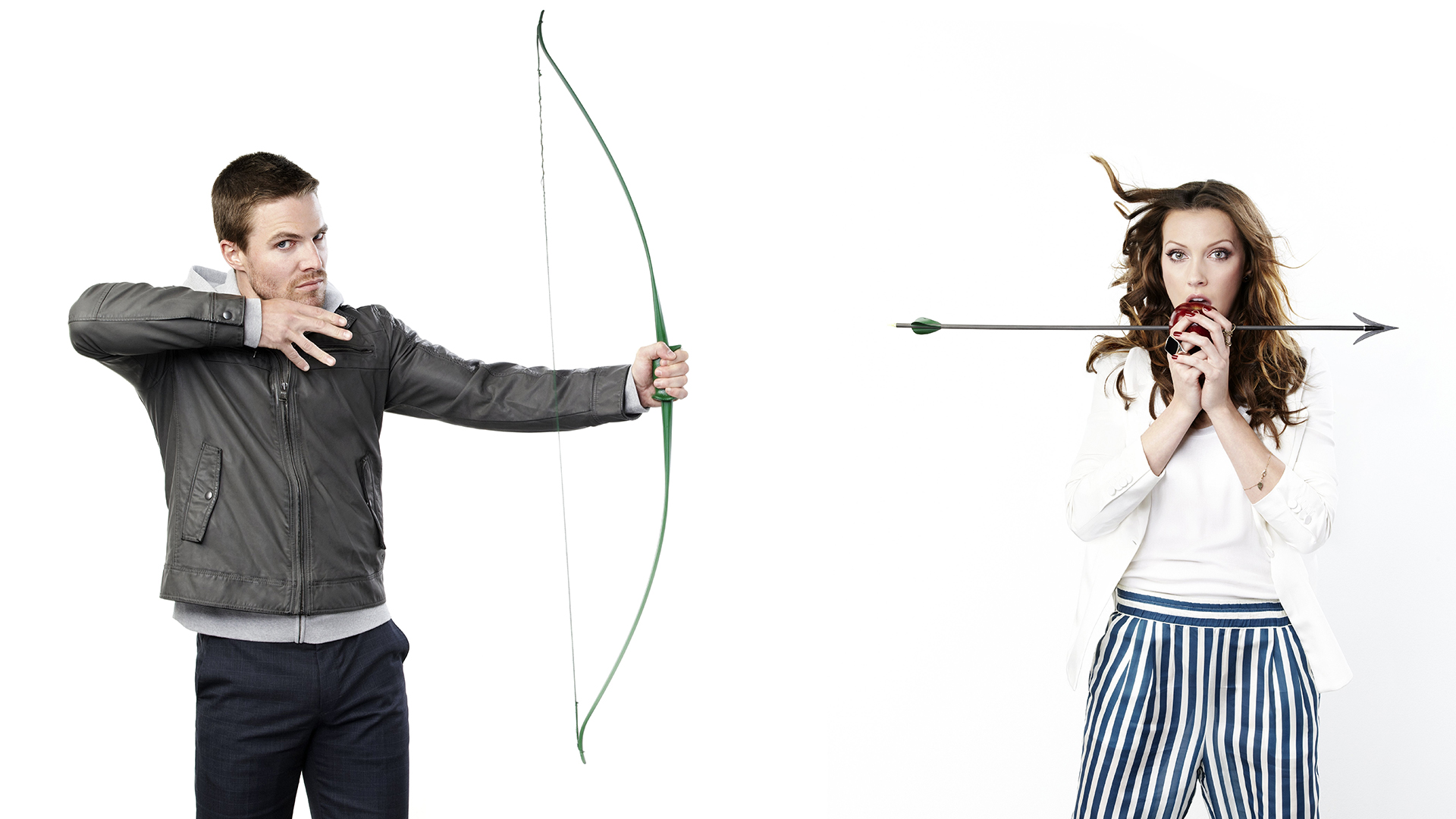 Man with bow and arrow aims at woman holding apple HD Wallpaper